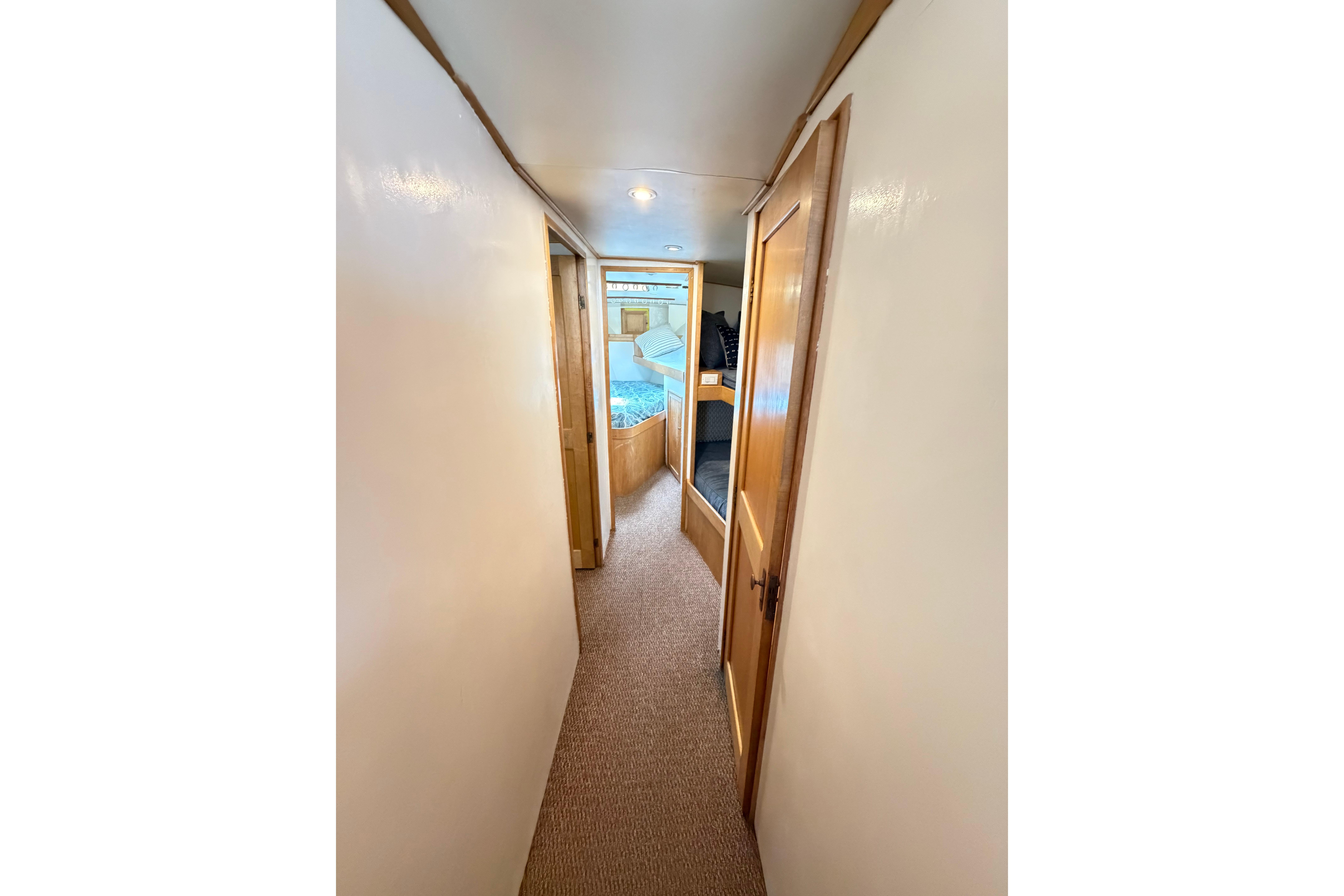 Narrow hallway inside 1998 Blackwell Custom Carolina Sportfish boat, featuring wooden doors and carpeted floor.
