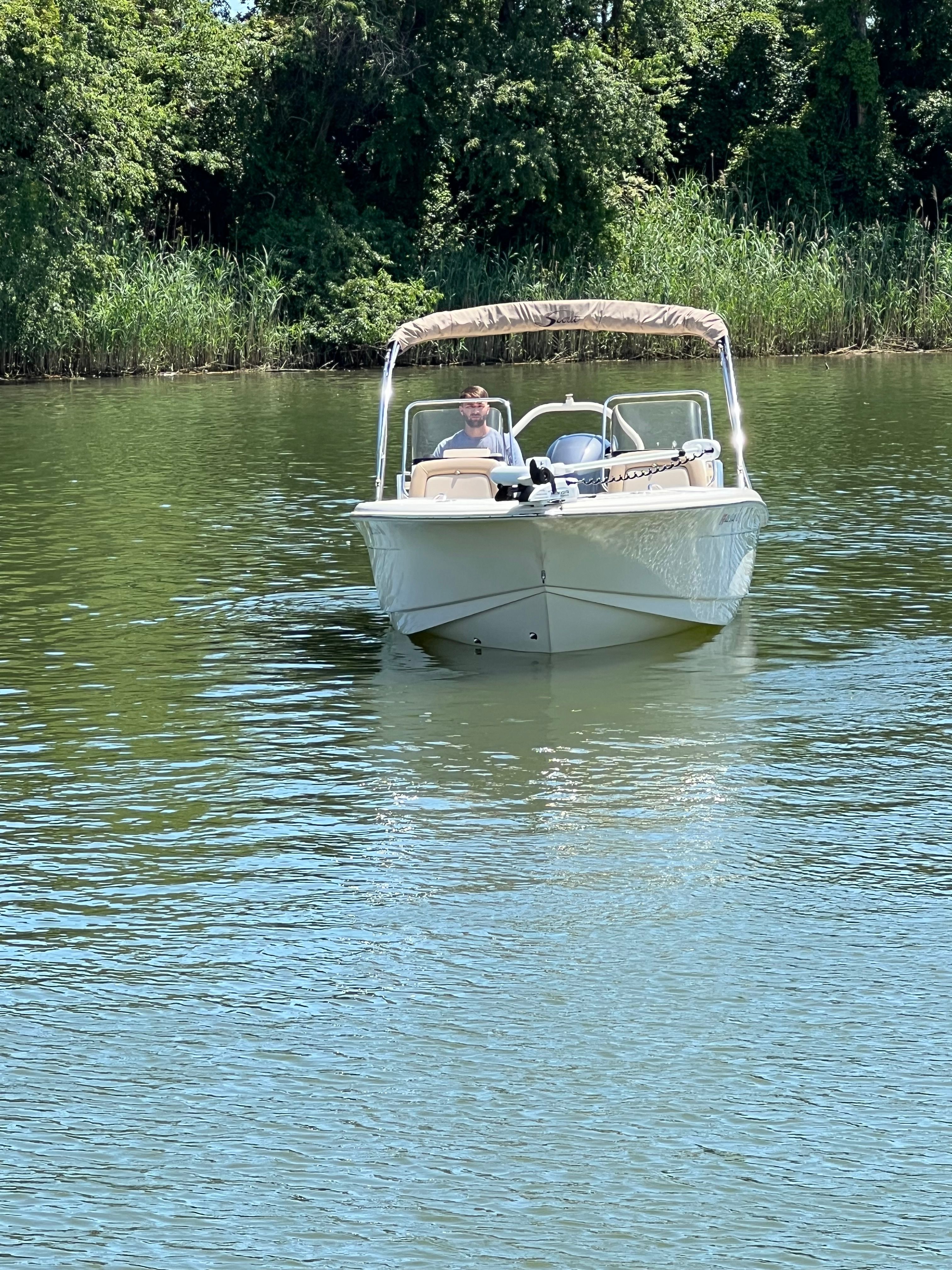 Scout 195 Sport Dorado from 2021 on calm water with lush background.