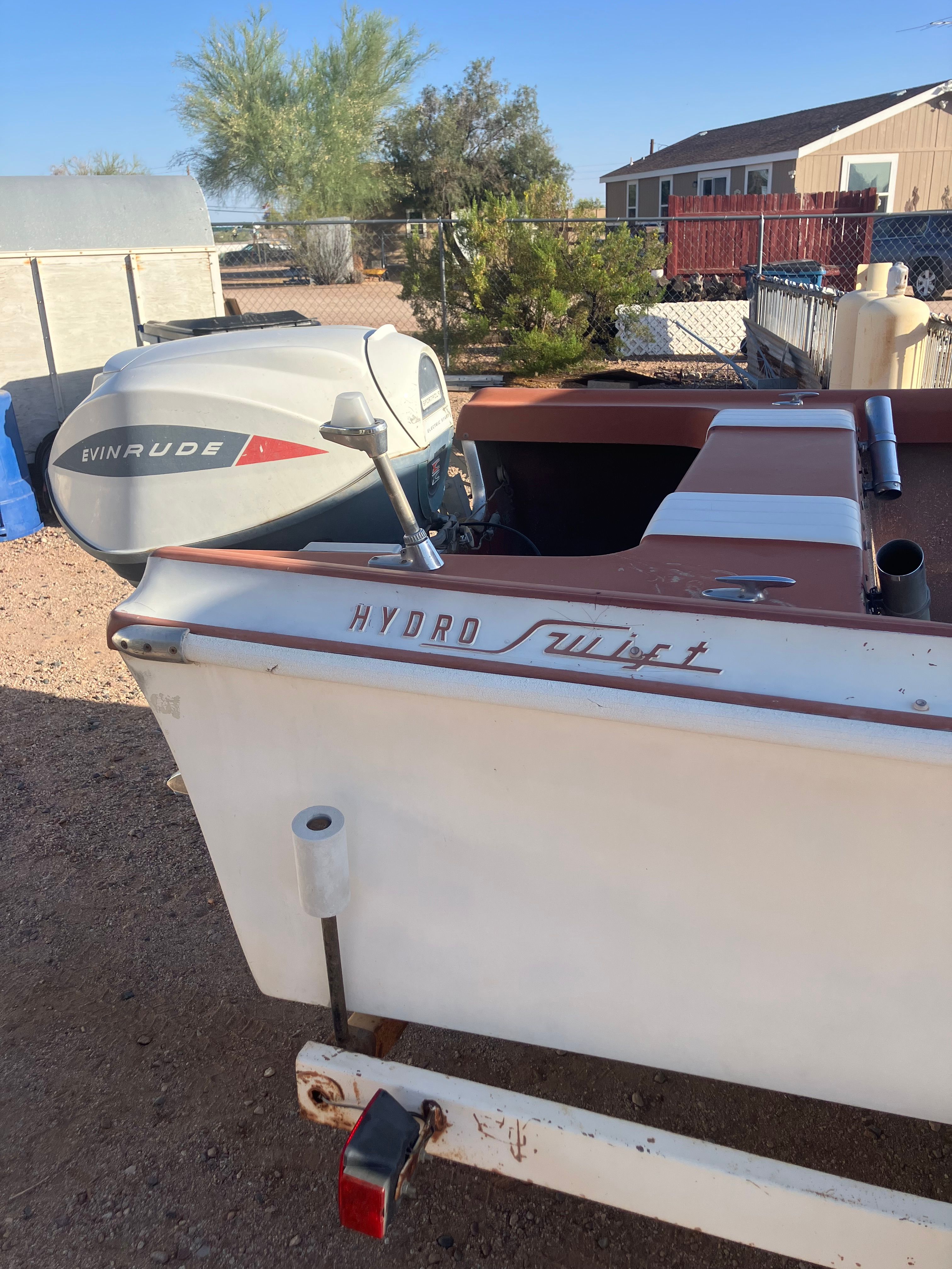 A 1958 Hydroswift Runabout with an Evinrude outboard motor, parked on a trailer outdoors.