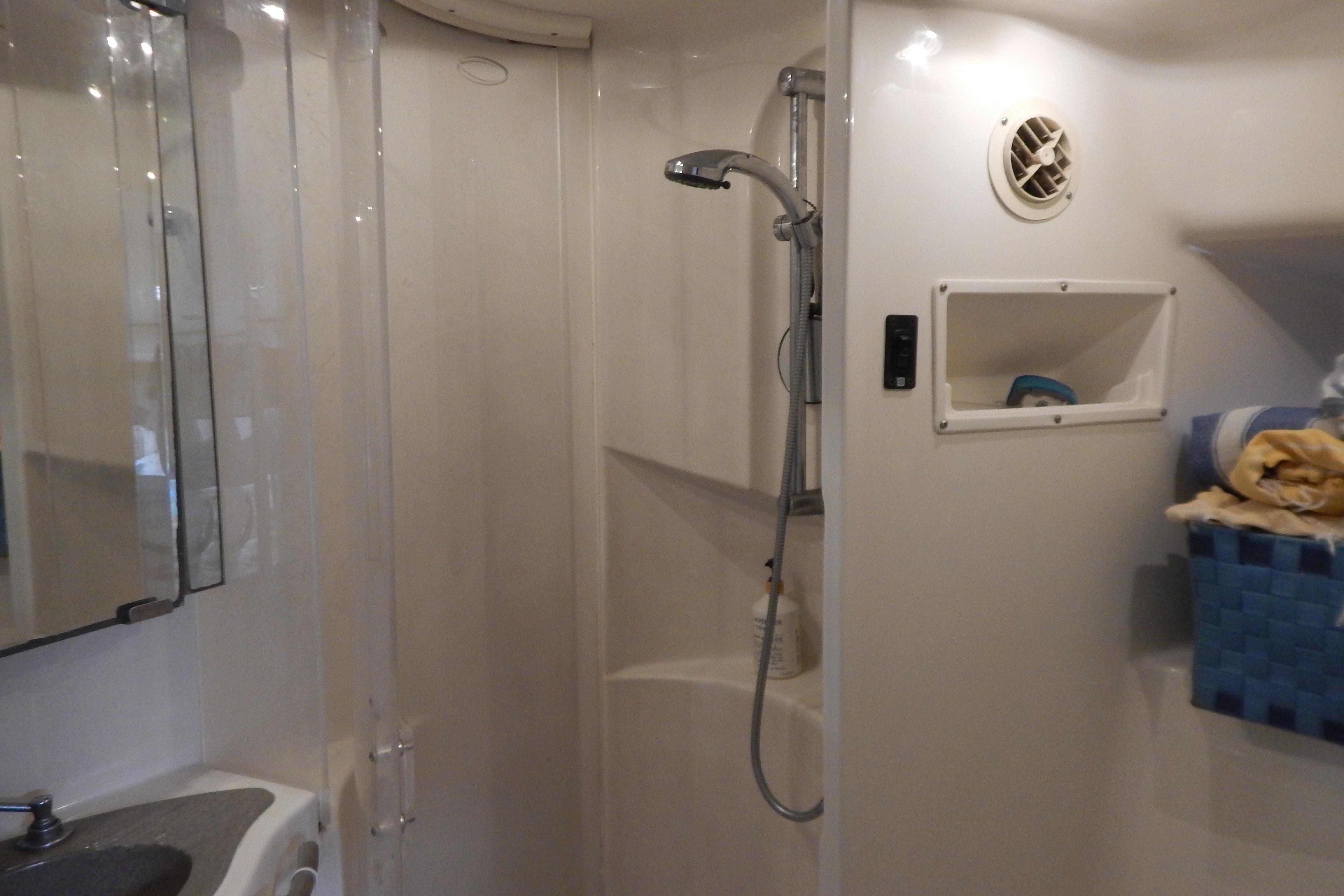 Compact bathroom in a 1998 Magnum 4100 SCR, featuring a shower and sink.