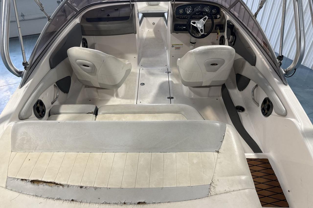 2012 Regal 1900 Bowrider interior with worn seating and steering wheel, showcasing spacious layout.
