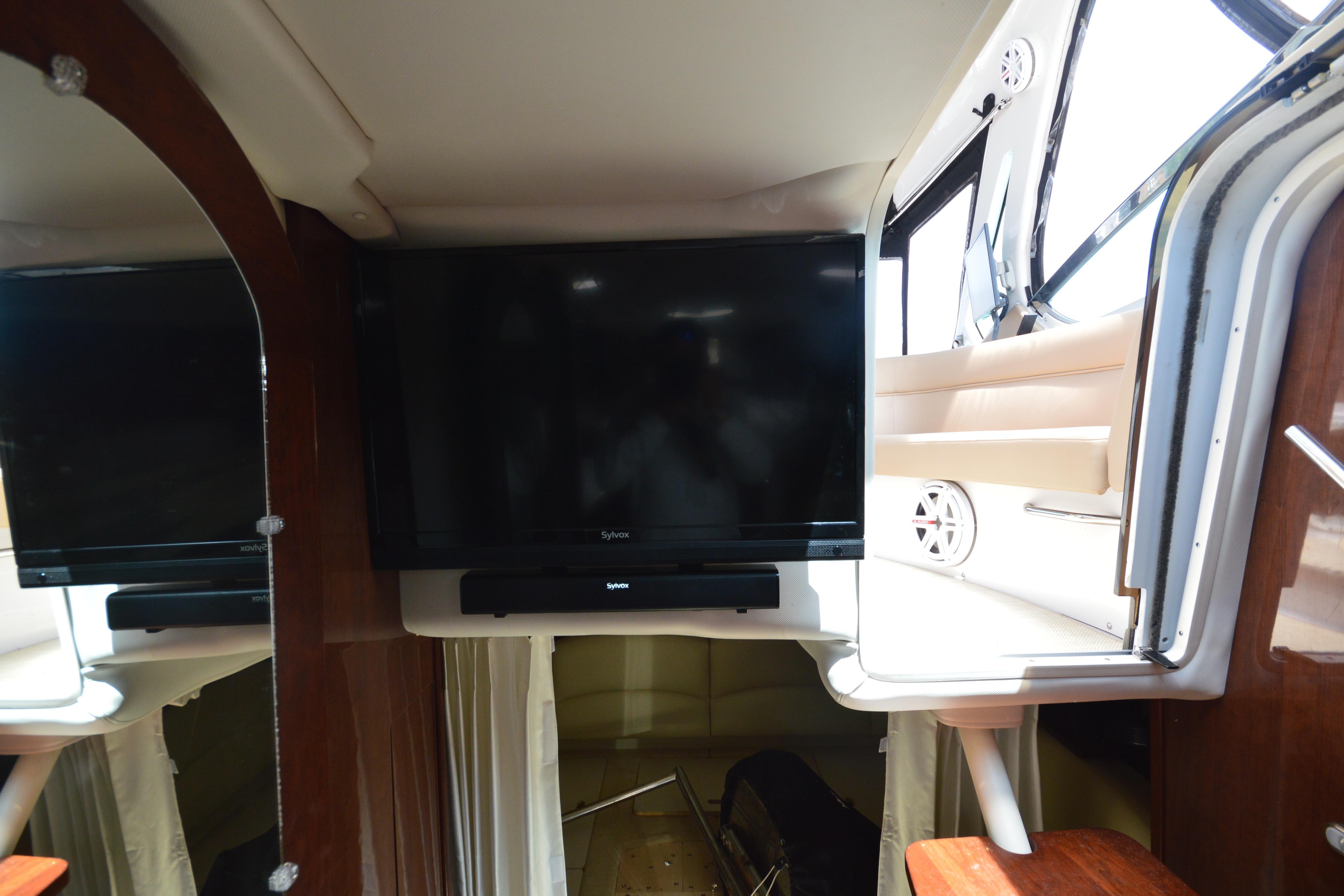 Interior of 2013 Four Winns V375 yacht with mounted flat-screen TV and wood accents.