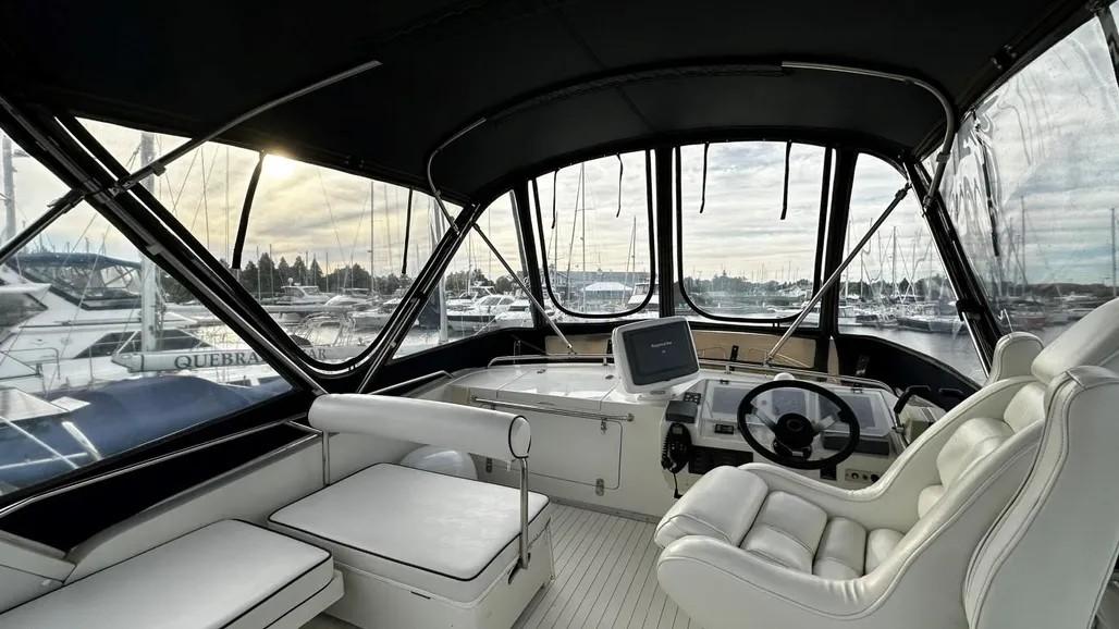 1985 Princess Sedan Flybridge interior with white seating and panoramic marina view.