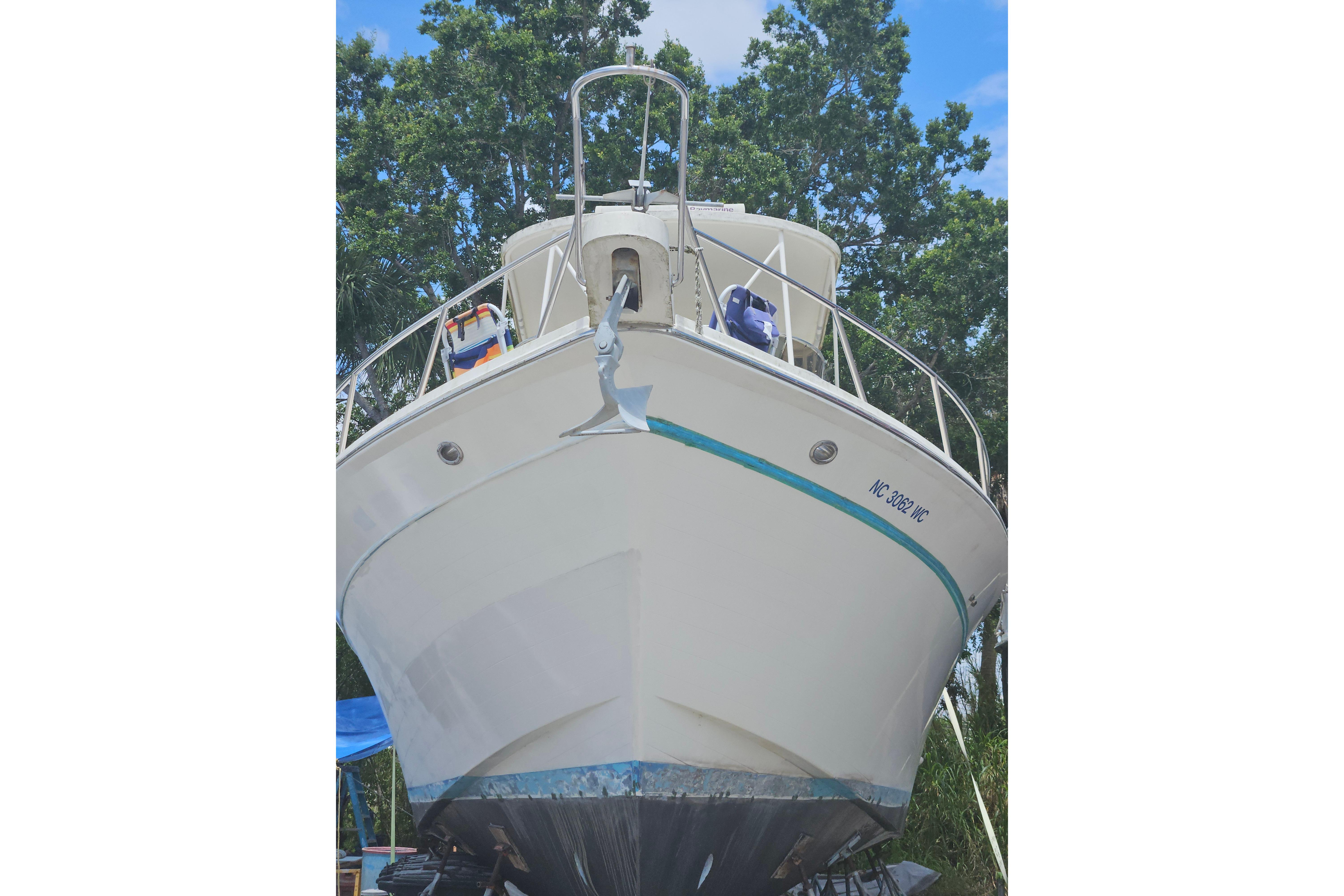 1991 Offshore Yachts 48 Yachtfisher on land, bow view, surrounded by trees.