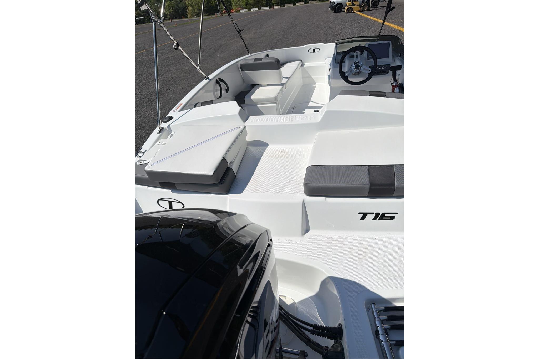 2026 Tahoe T16 boat interior with seating and steering wheel, parked on pavement.
