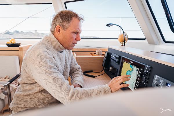 Man navigating on Nautitech 44 Open yacht, 2025 model, using touchscreen controls.