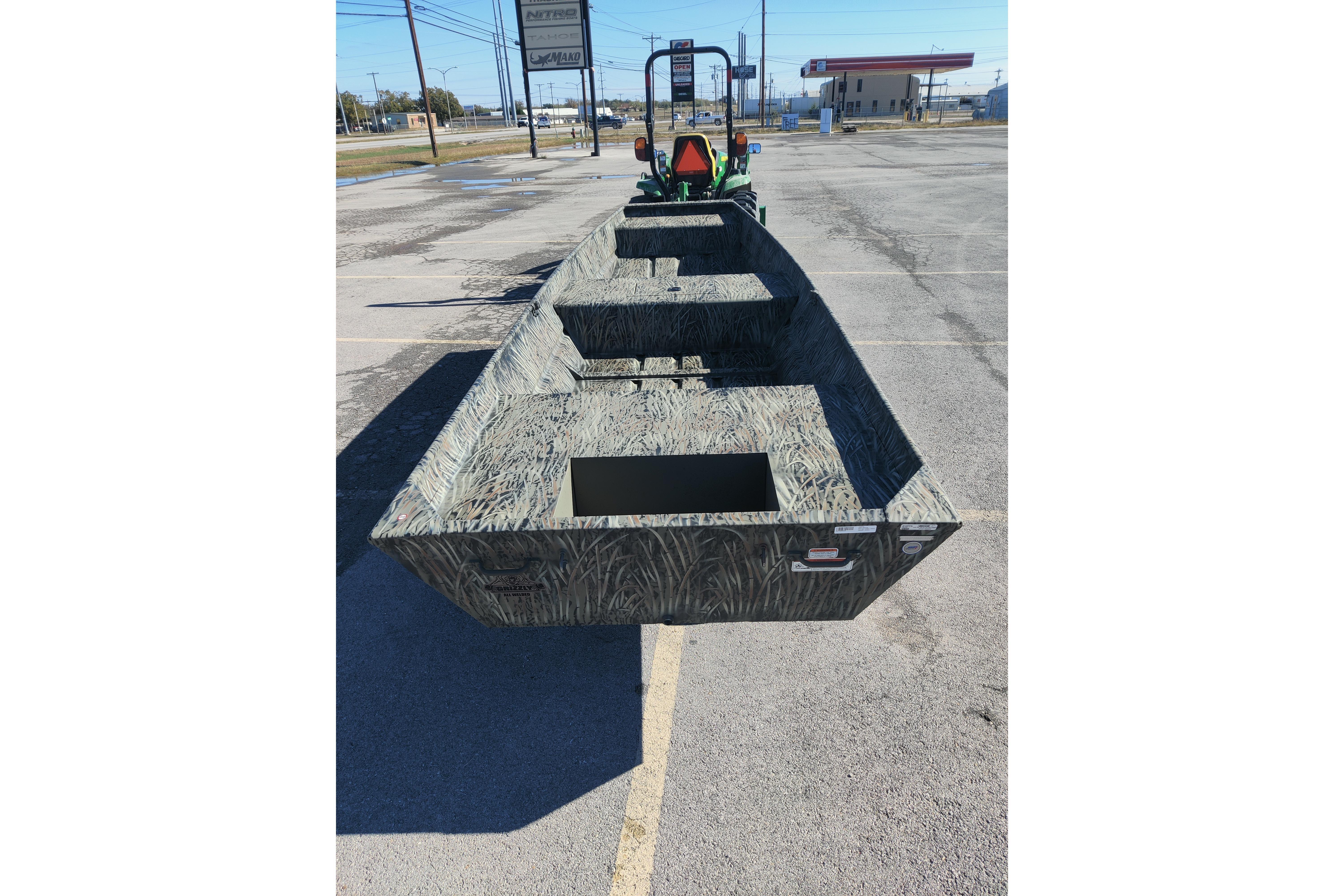 2026 Tracker Grizzly 15 Jon boat in parking lot, showcasing rugged design and spacious interior.