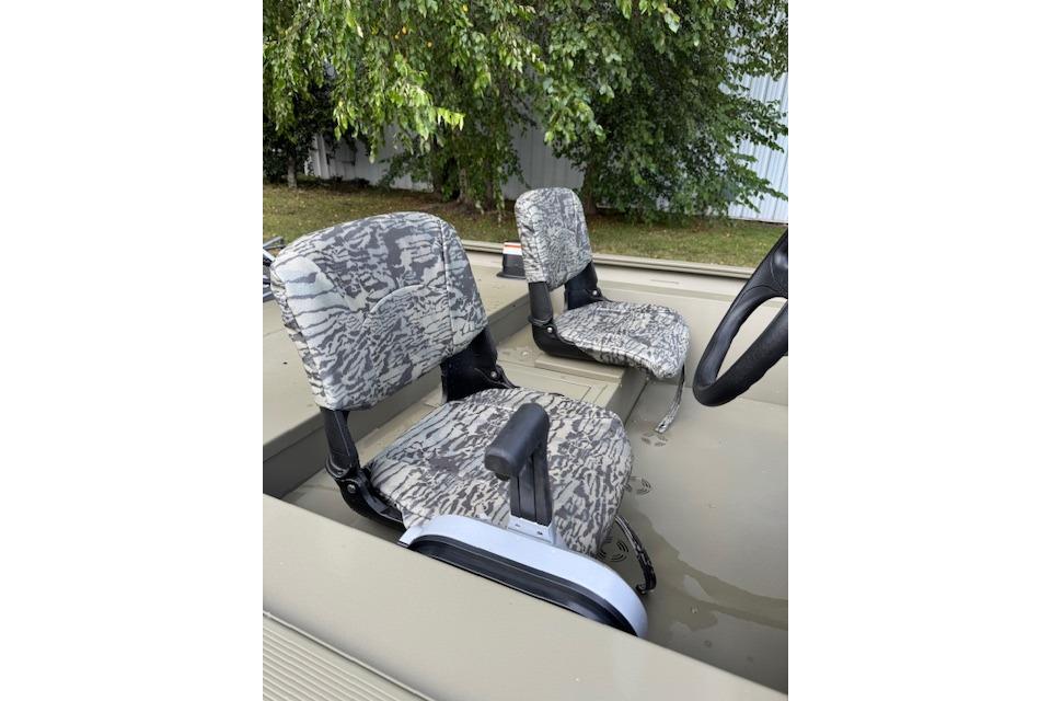 Camouflage seats in a 2026 Tracker Grizzly 1754 SC boat, surrounded by greenery.