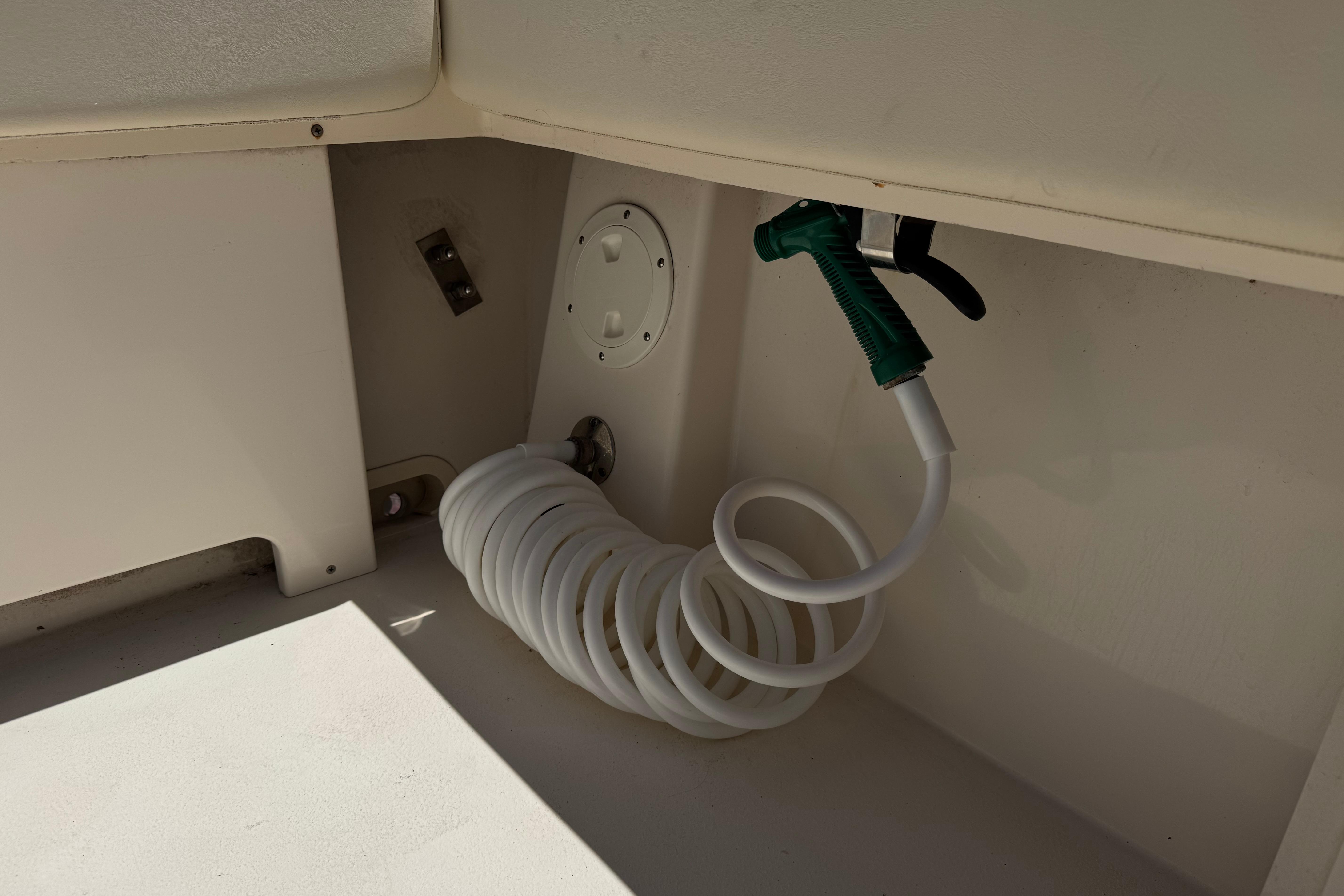 Coiled hose and nozzle in 2017 Defiance Admiral 220 EX boat compartment.