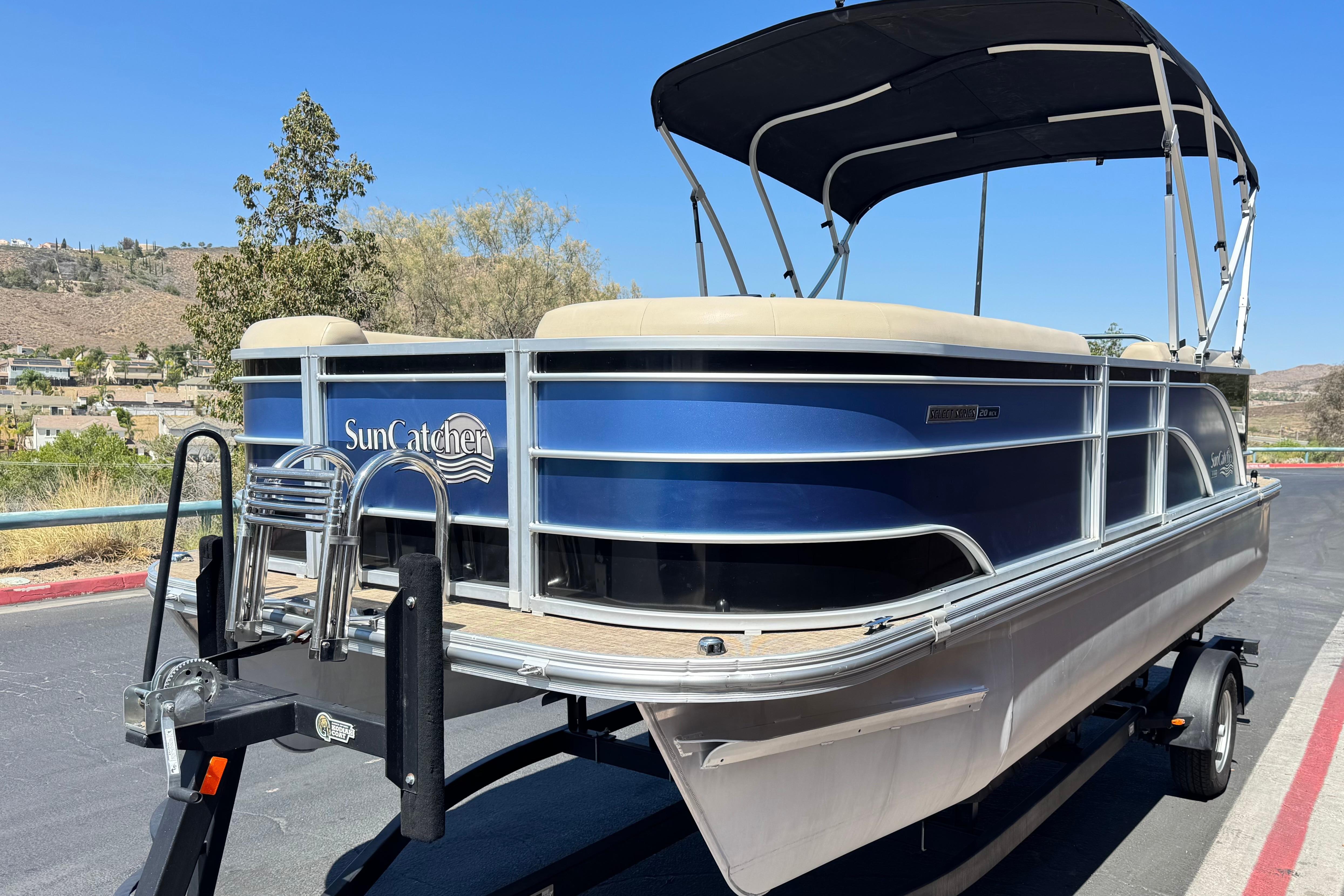 2021 SunCatcher Select 20RCX pontoon boat on trailer, blue and beige design, sunny outdoor setting.