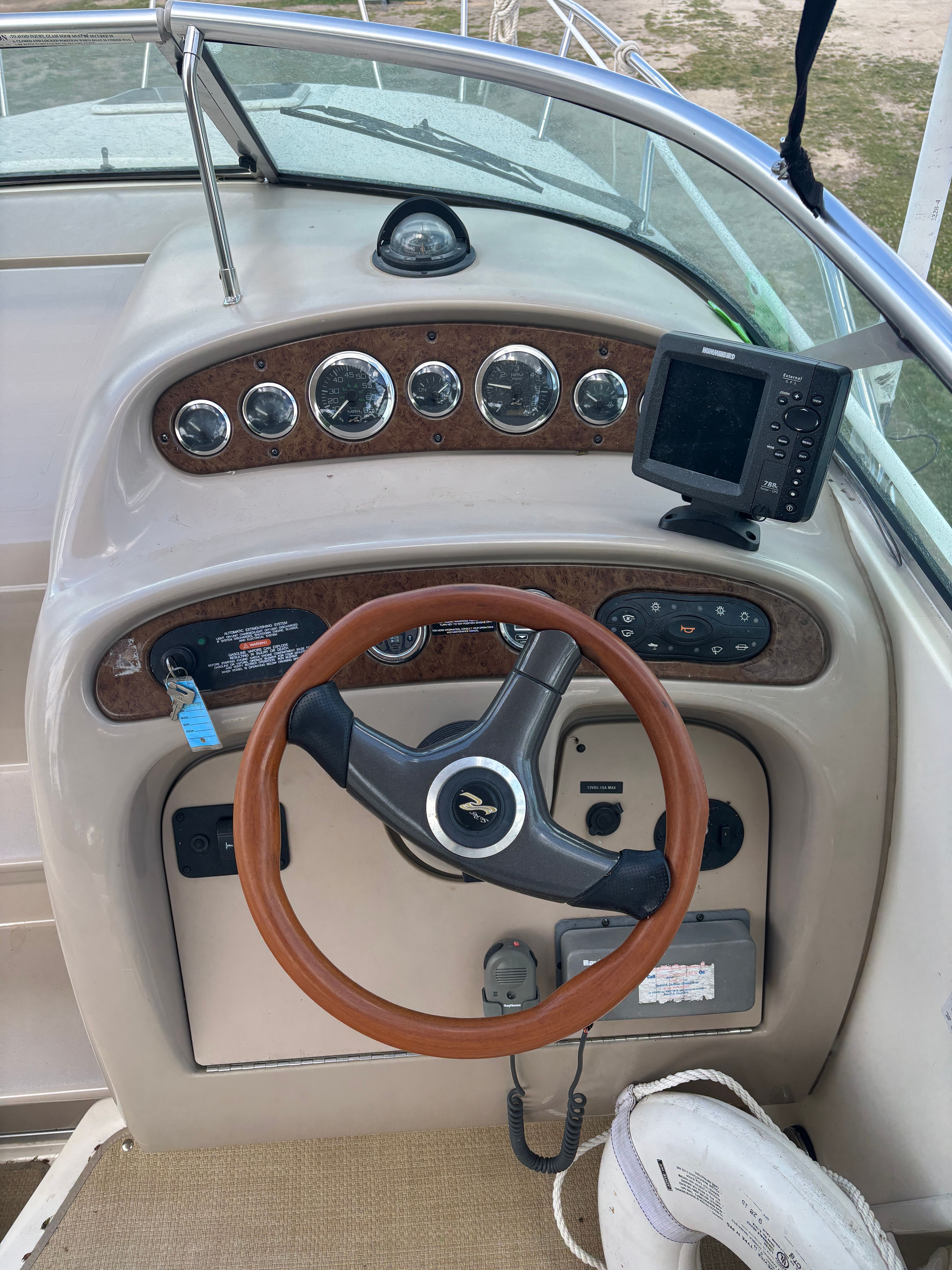 The image shows the helm of a Sea Ray Sundancer 260 boat with a wooden steering wheel and instruments.