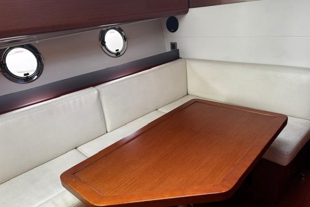 Interior of 2013 Beneteau Gran Turismo 38 yacht with wooden table and white seating.