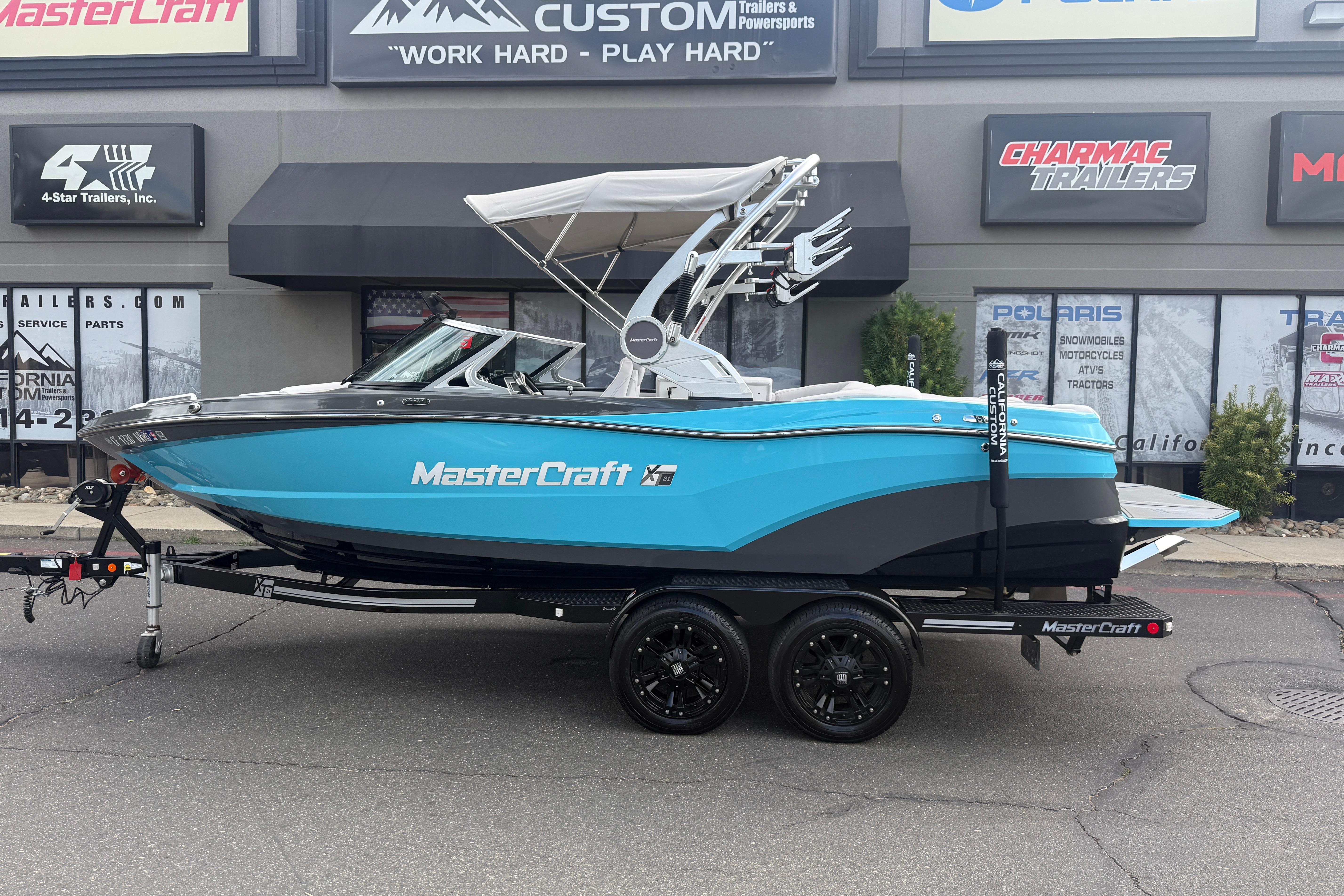 2018 MasterCraft XT21 boat in blue on trailer, parked outside dealership.
