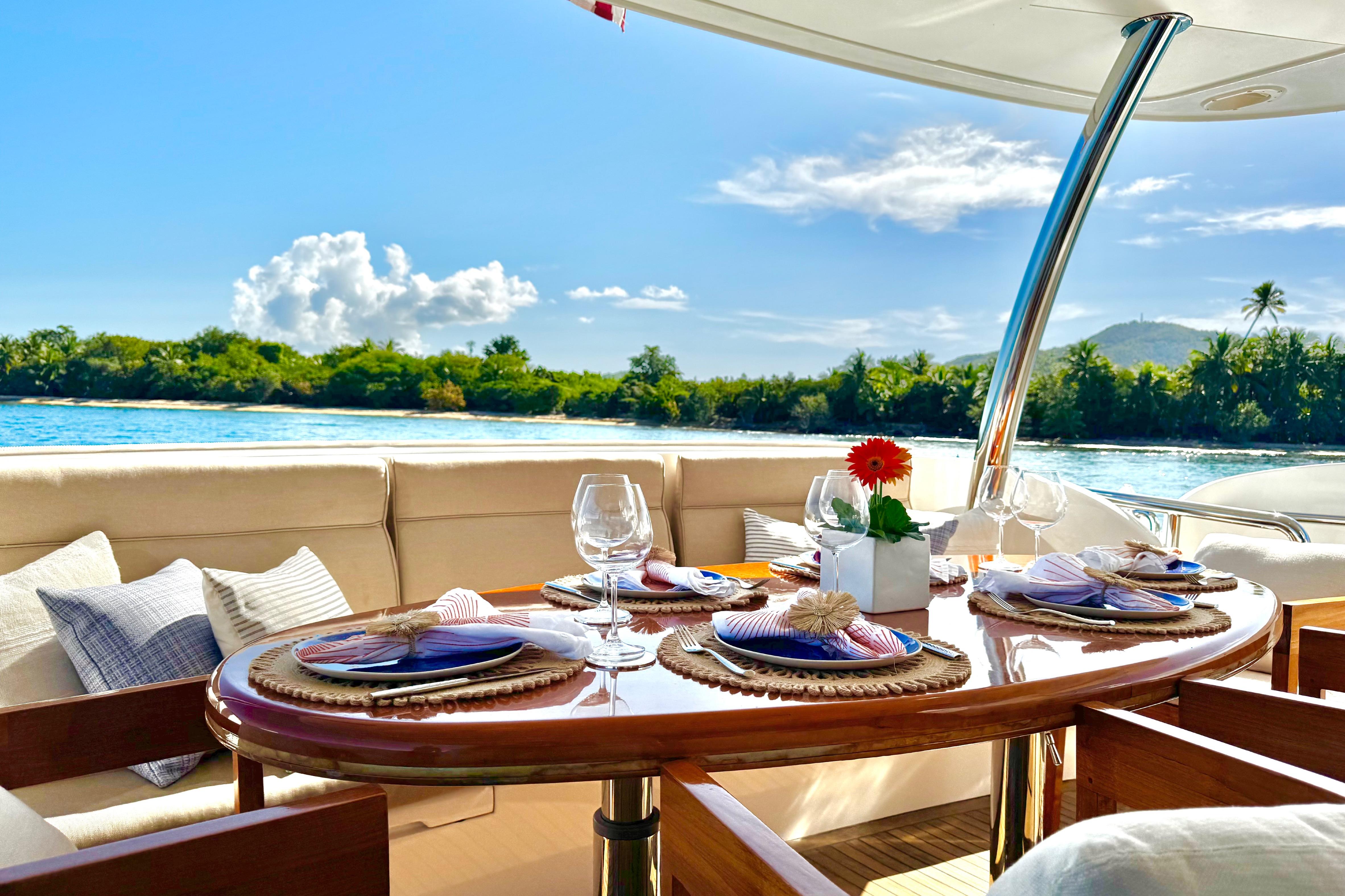 Luxurious Horizon E88 yacht dining area with elegant table setting, ocean view, and tropical backdrop.