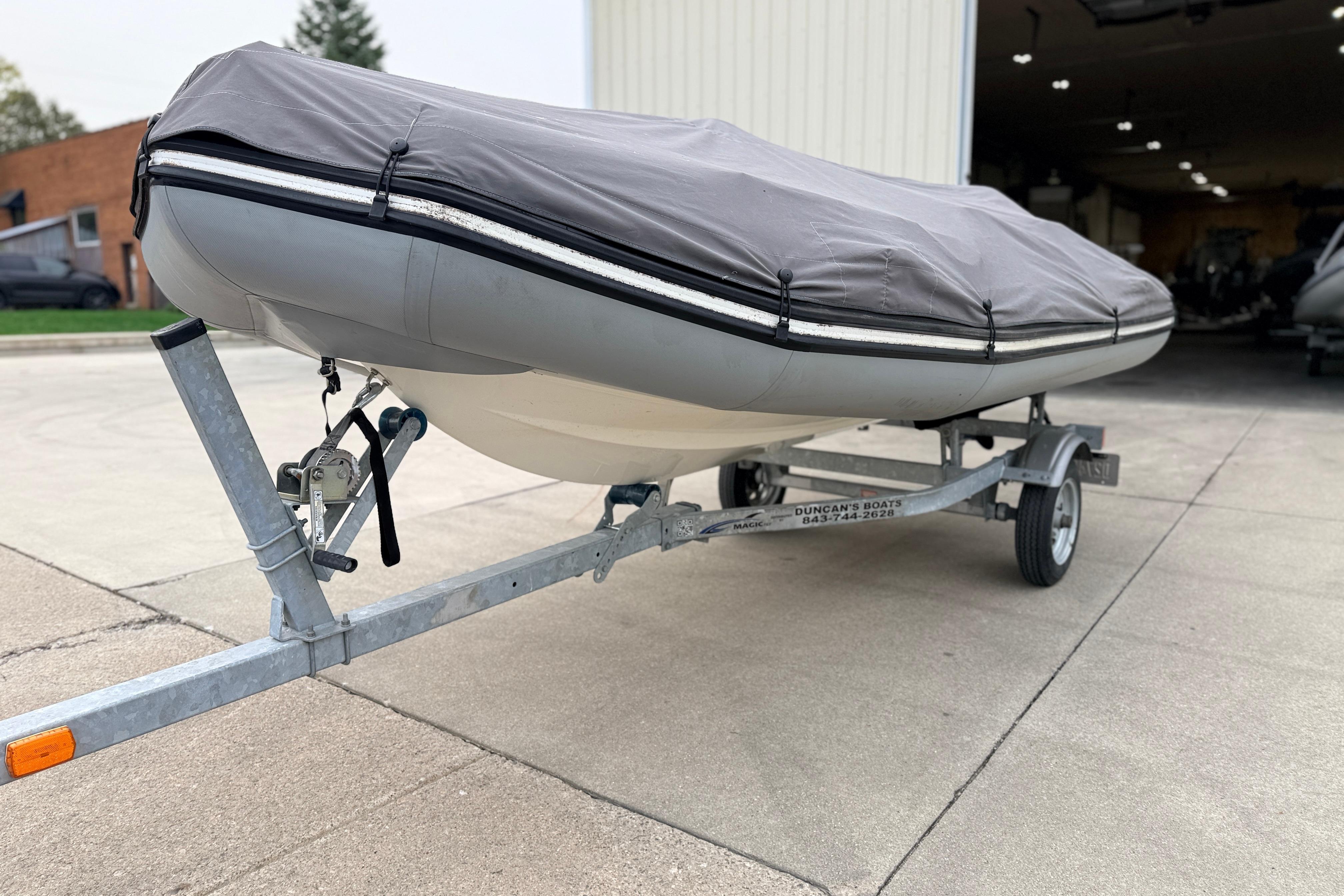 2014 Zodiac Pro Classic 420 boat on trailer, covered, parked outside a garage.