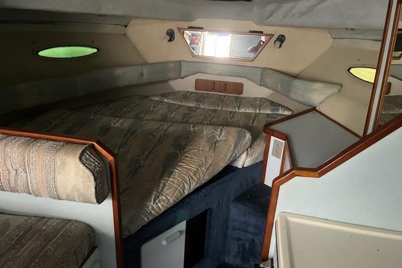 1989 Sea Ray 300 Sundancer cabin interior with cozy sleeping area and nautical decor.