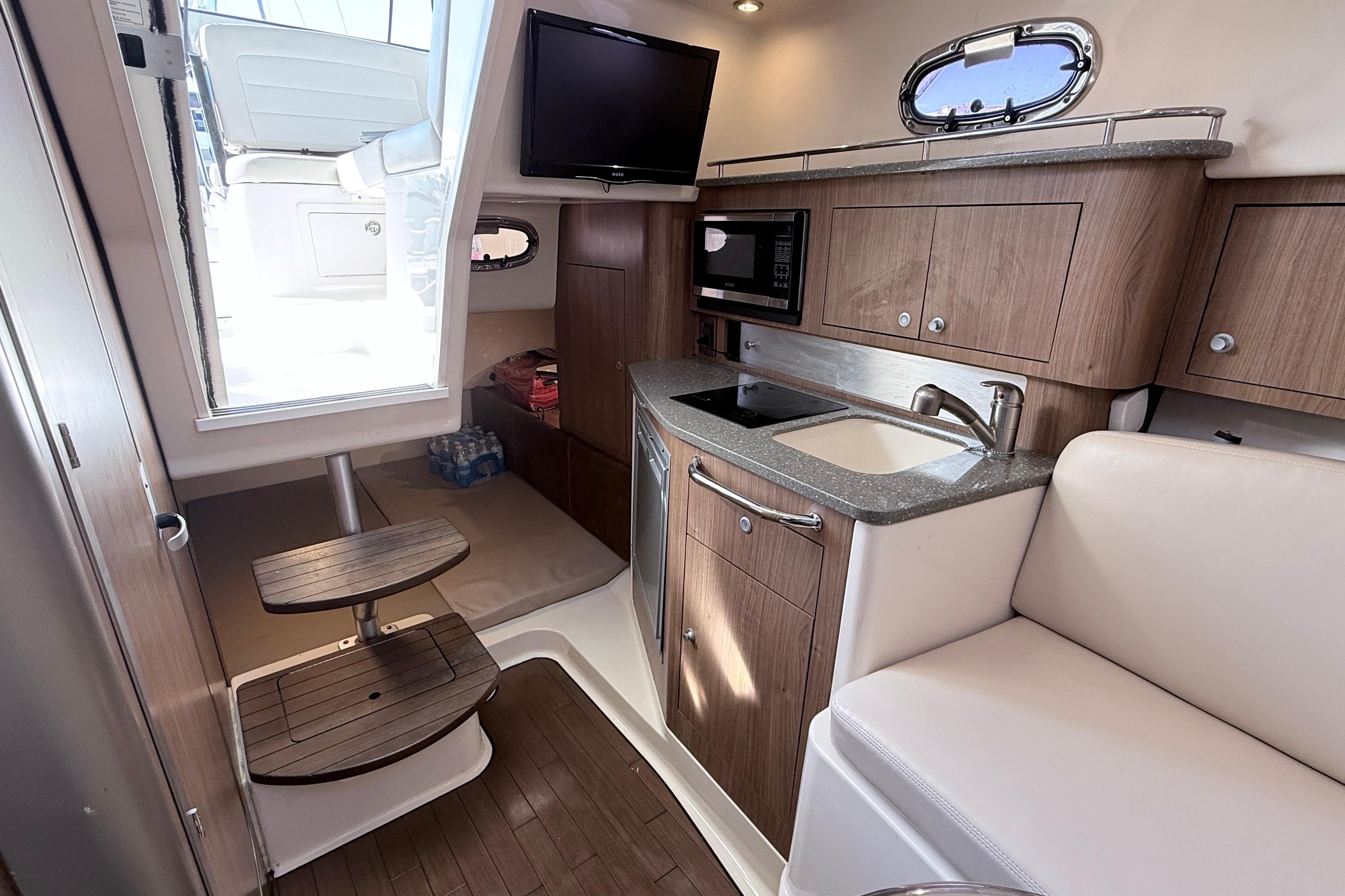 2018 Boston Whaler 315 Conquest cabin interior with kitchenette and seating area.