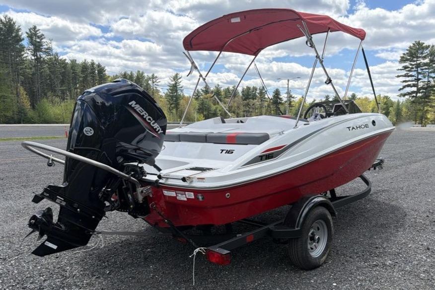 2026 Tahoe T16 boat with Mercury engine, red and white design, parked outdoors.