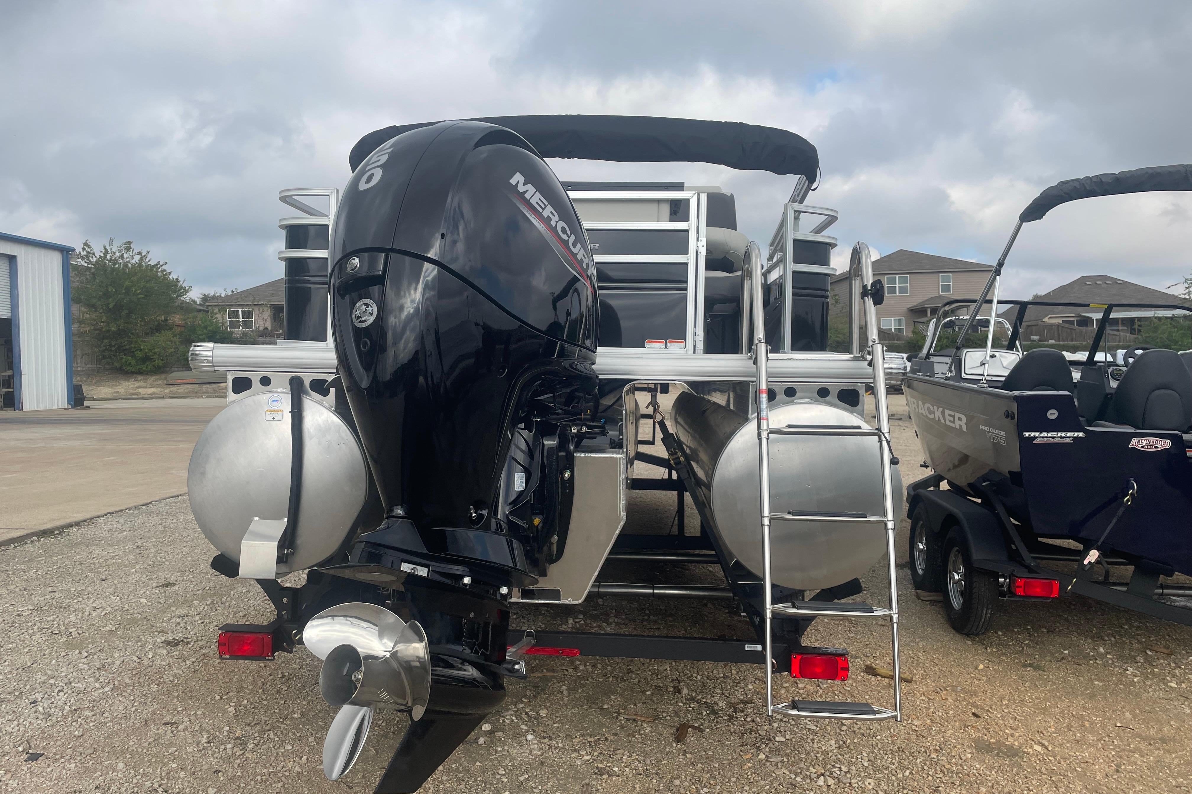 2026 Sun Tracker Fishin' Barge 22 XP3 with Mercury outboard motor, parked outdoors.