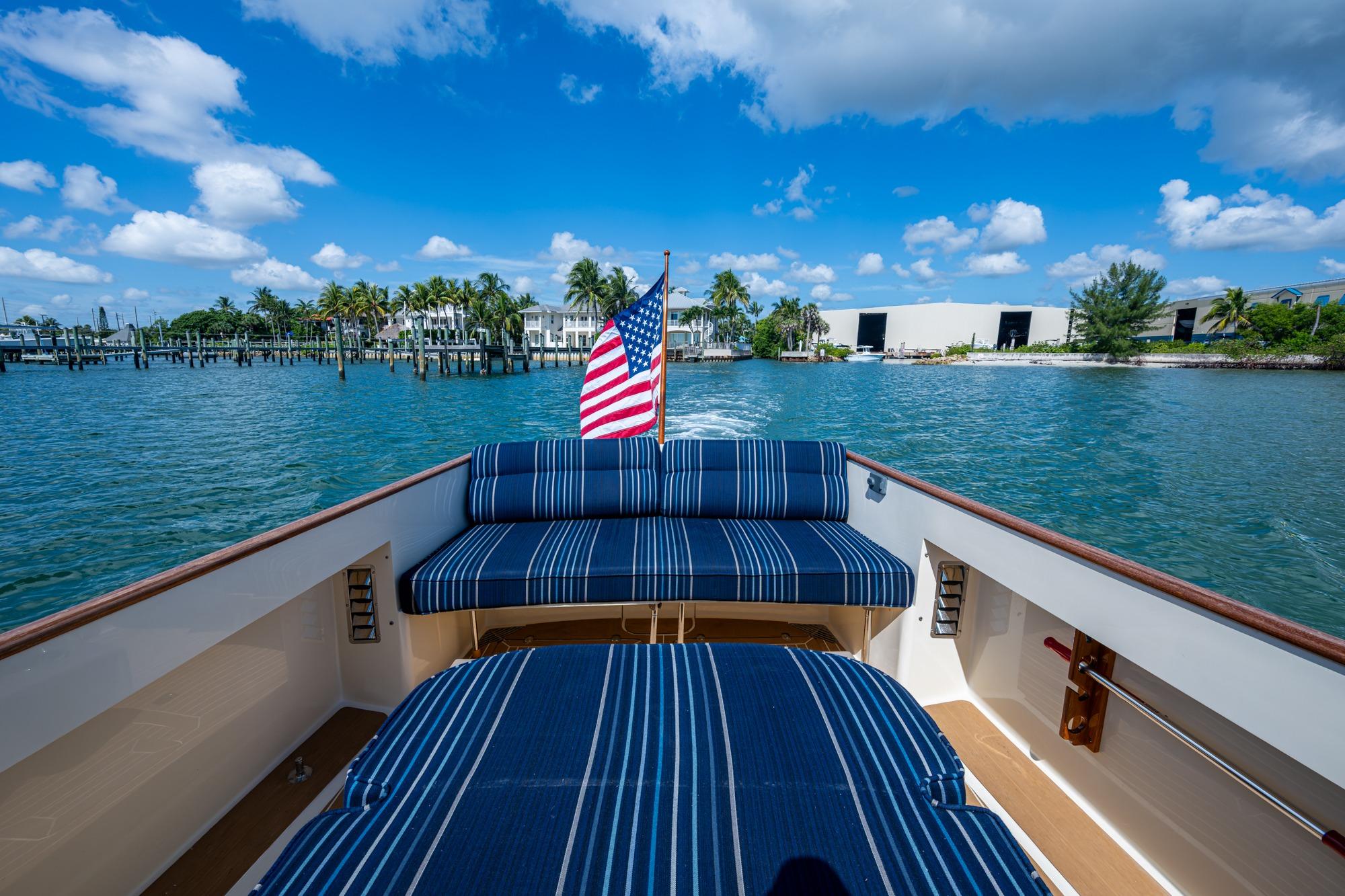 2001 Hinckley Picnic Boat Classic cruising with American flag, blue striped seating, and scenic waterfront.