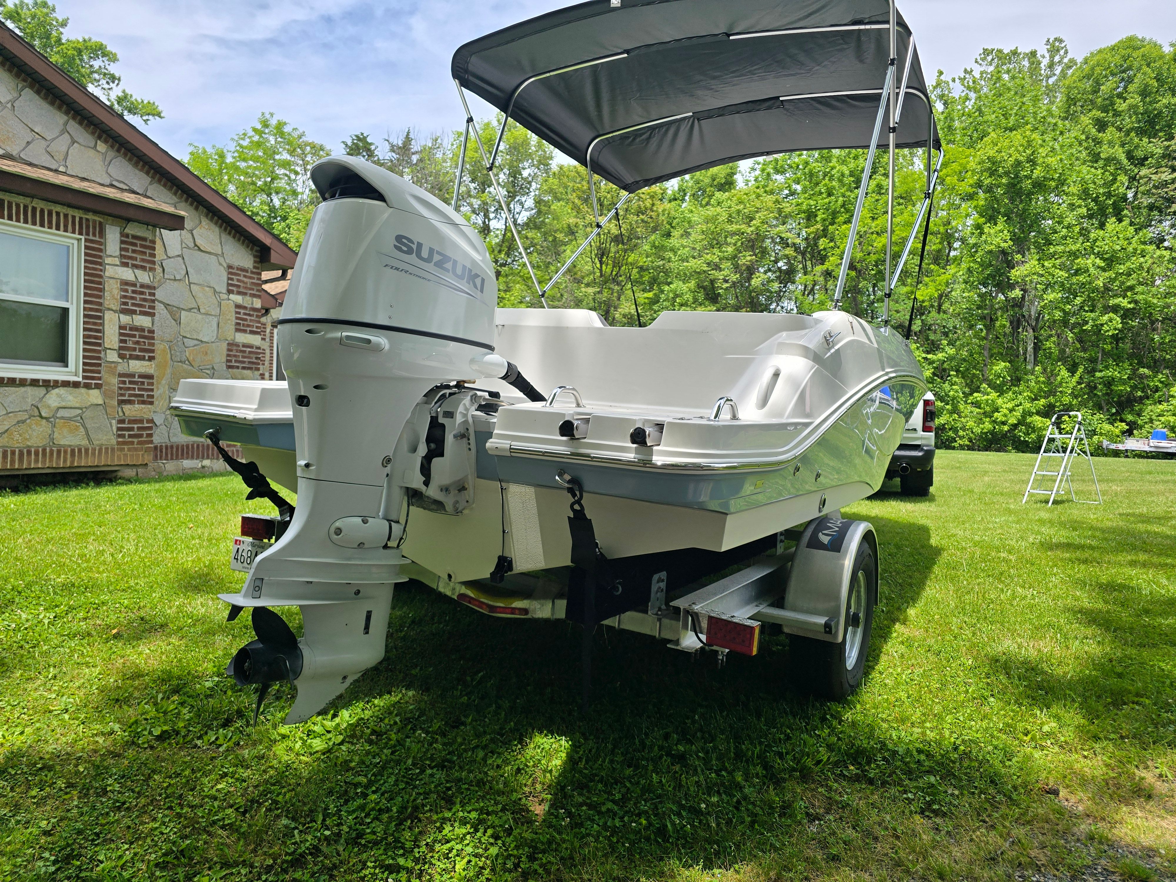 2021 Hurricane 205SS boat with Suzuki engine in a garden.
