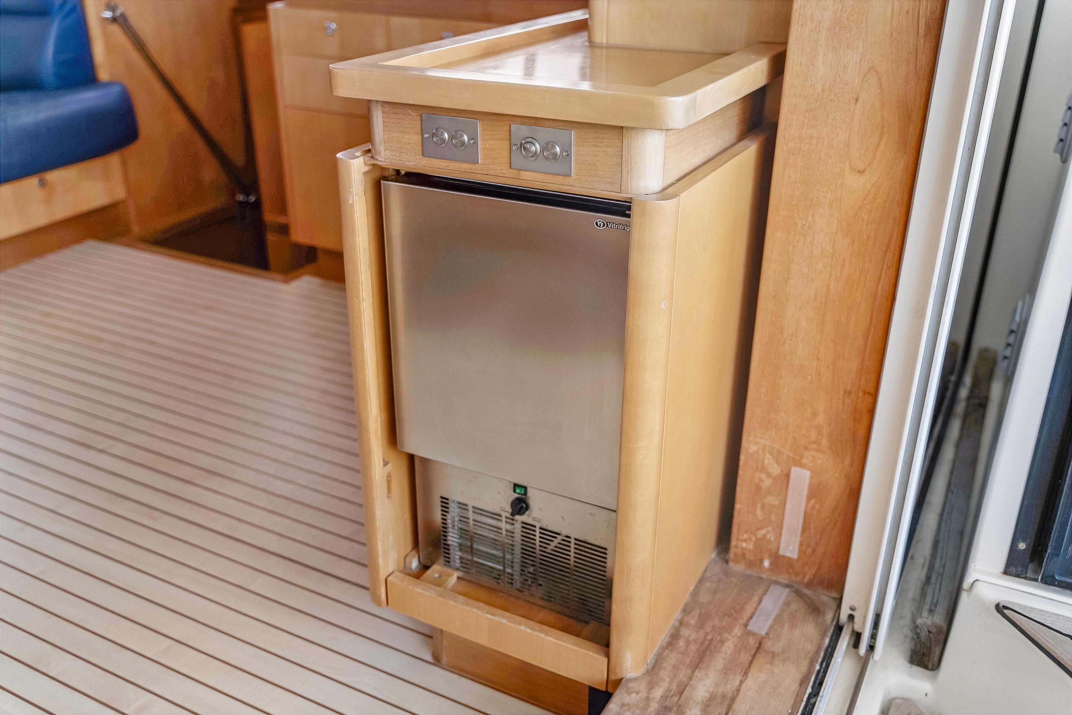 Compact fridge in 2009 Catana 65 yacht interior, featuring wooden cabinetry and sleek design.