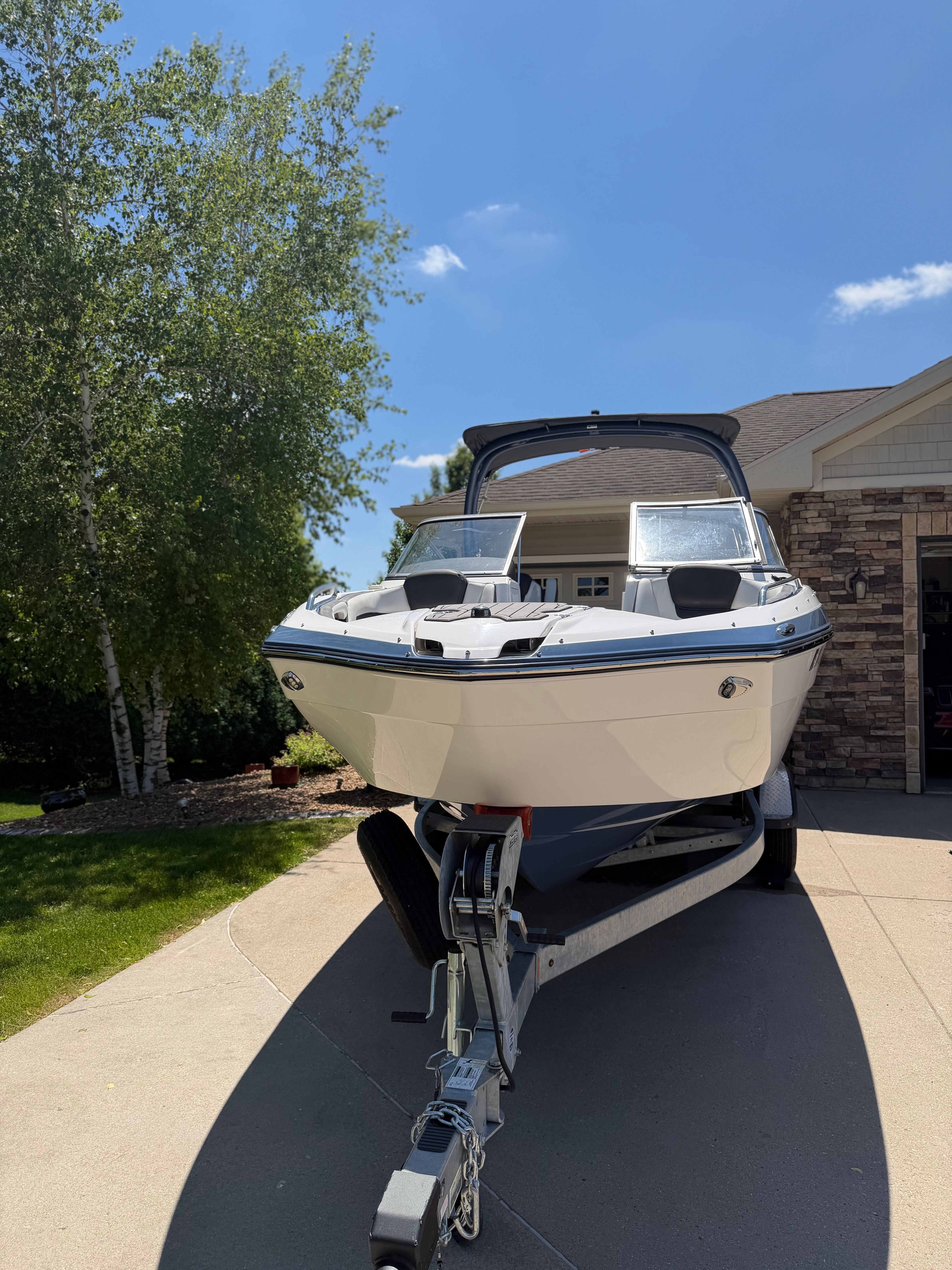 A 2018 Yamaha 242 Limited S boat on a trailer in a driveway.