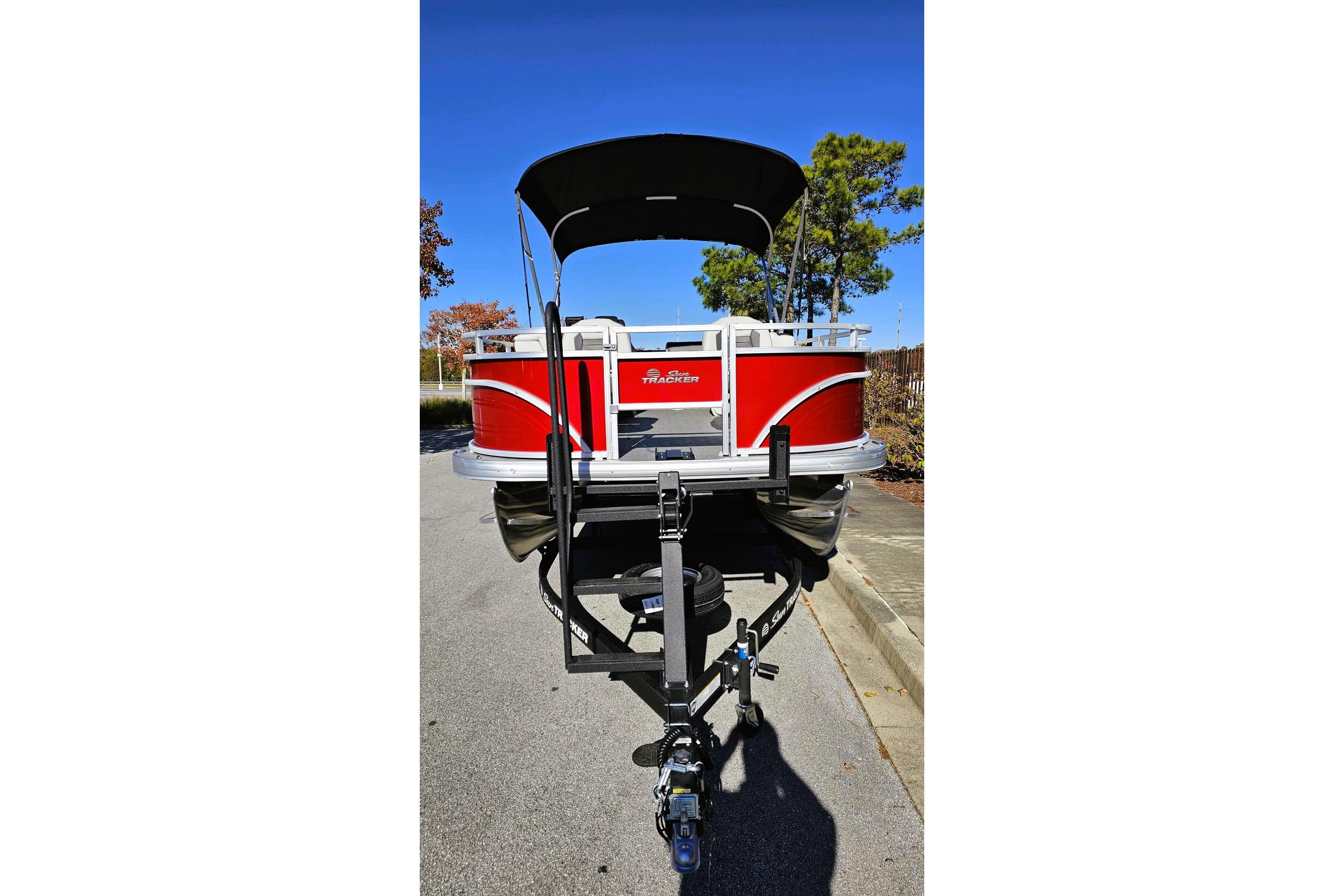 2026 Sun Tracker Fishin' Barge 22 DLX pontoon boat on trailer, red exterior, sunny day.