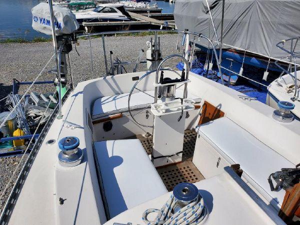1977 Ontario Yachts 32 sailboat cockpit with steering wheel and winches, docked near water.