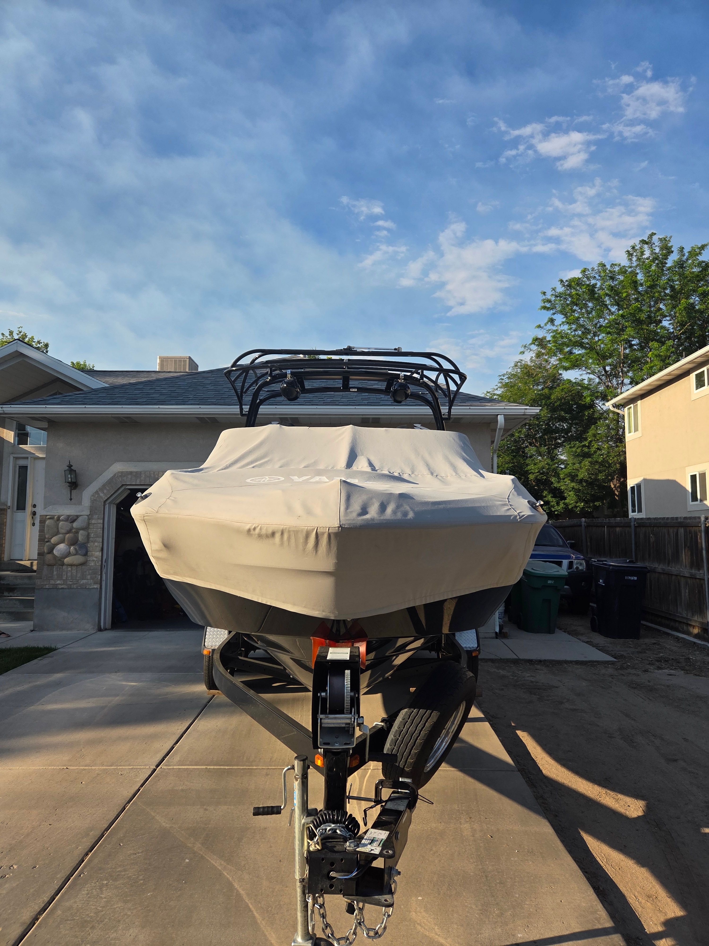 A 2016 Yamaha 242X E-Series boat on a trailer in a driveway.