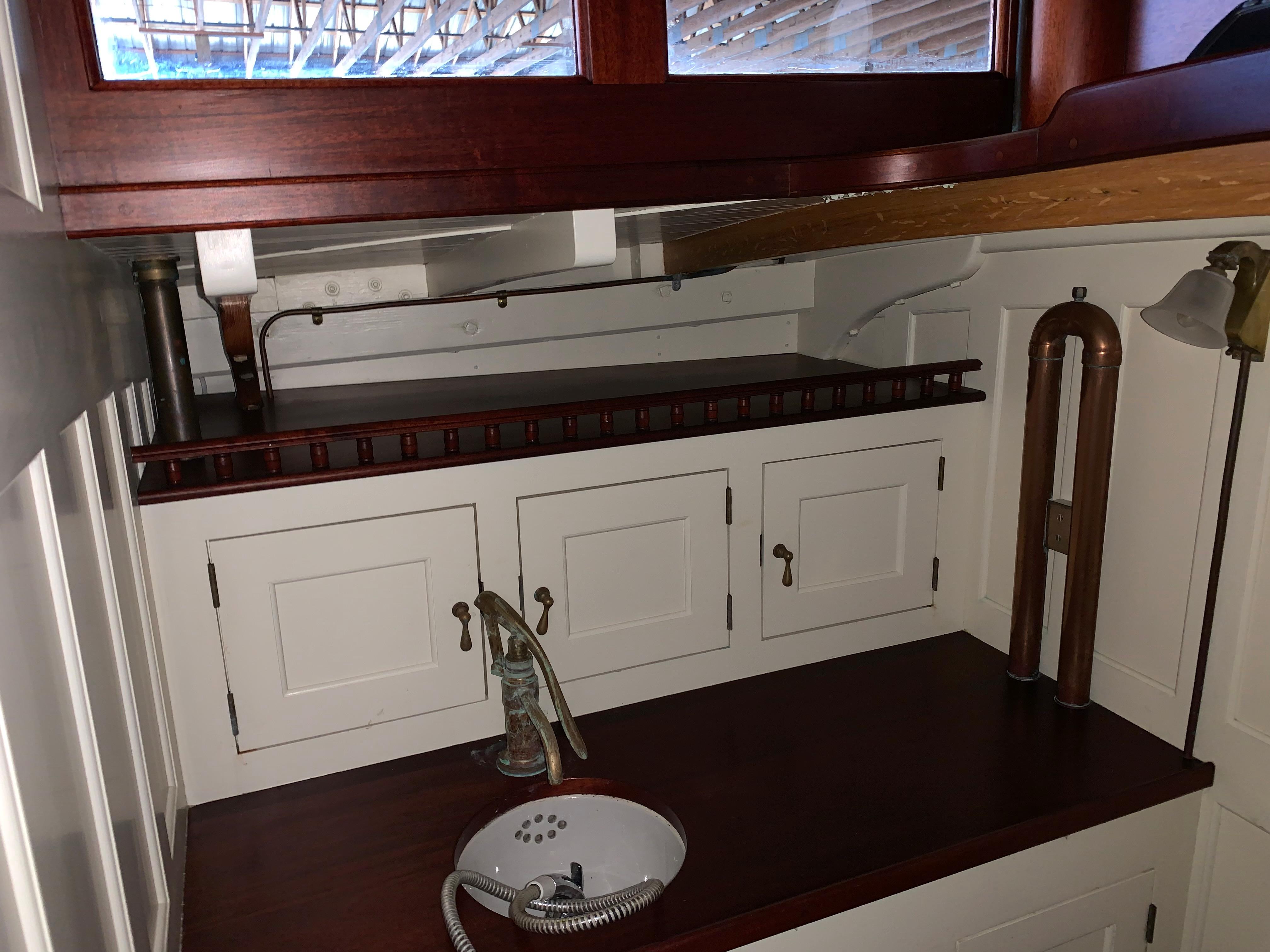 Interior of 1902 Herreshoff Gaff Cutter, featuring vintage cabinetry and sink.