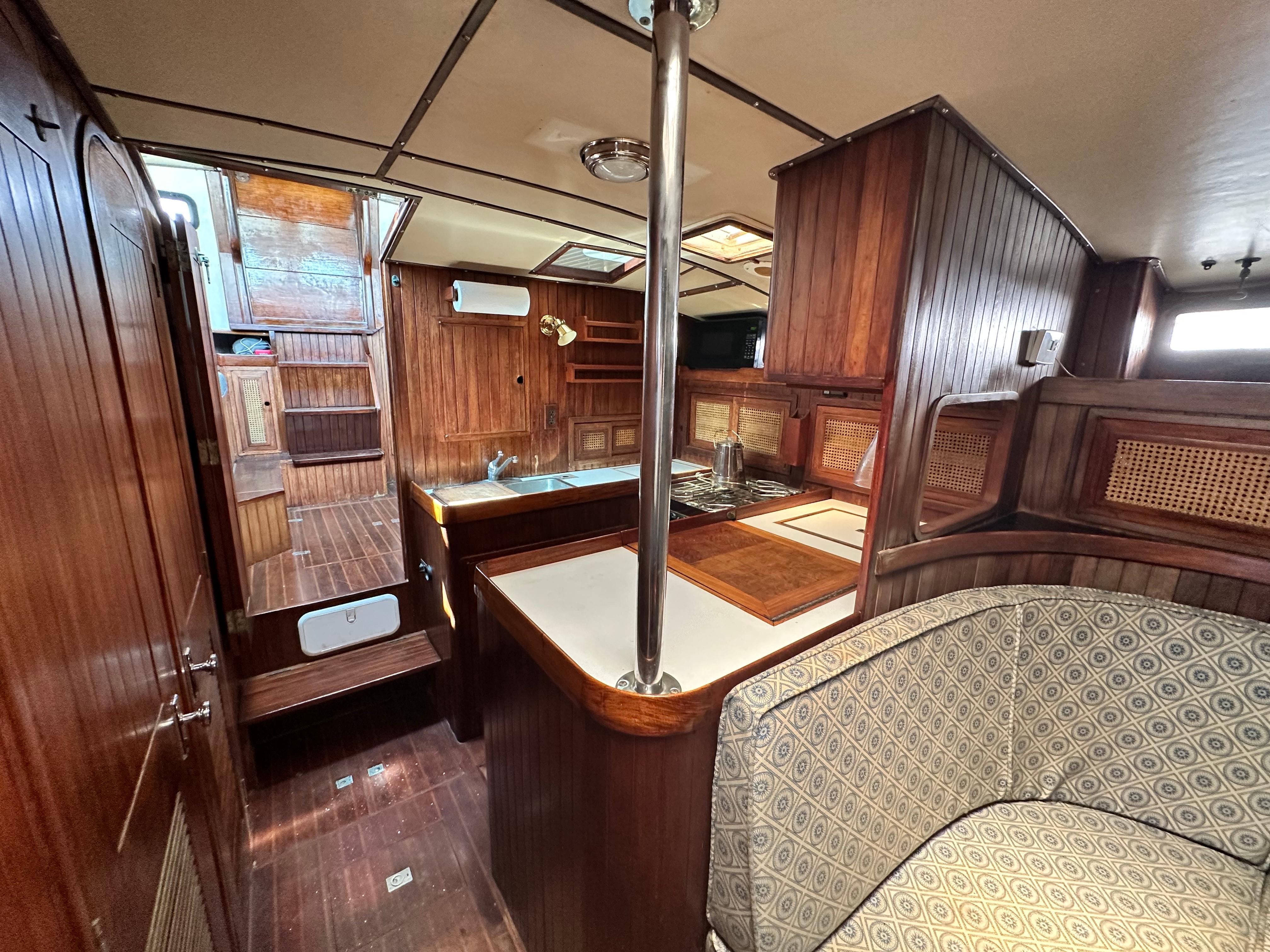 Interior of 1982 Pan Oceanic 43 sailboat with wooden cabinetry and cozy seating area.