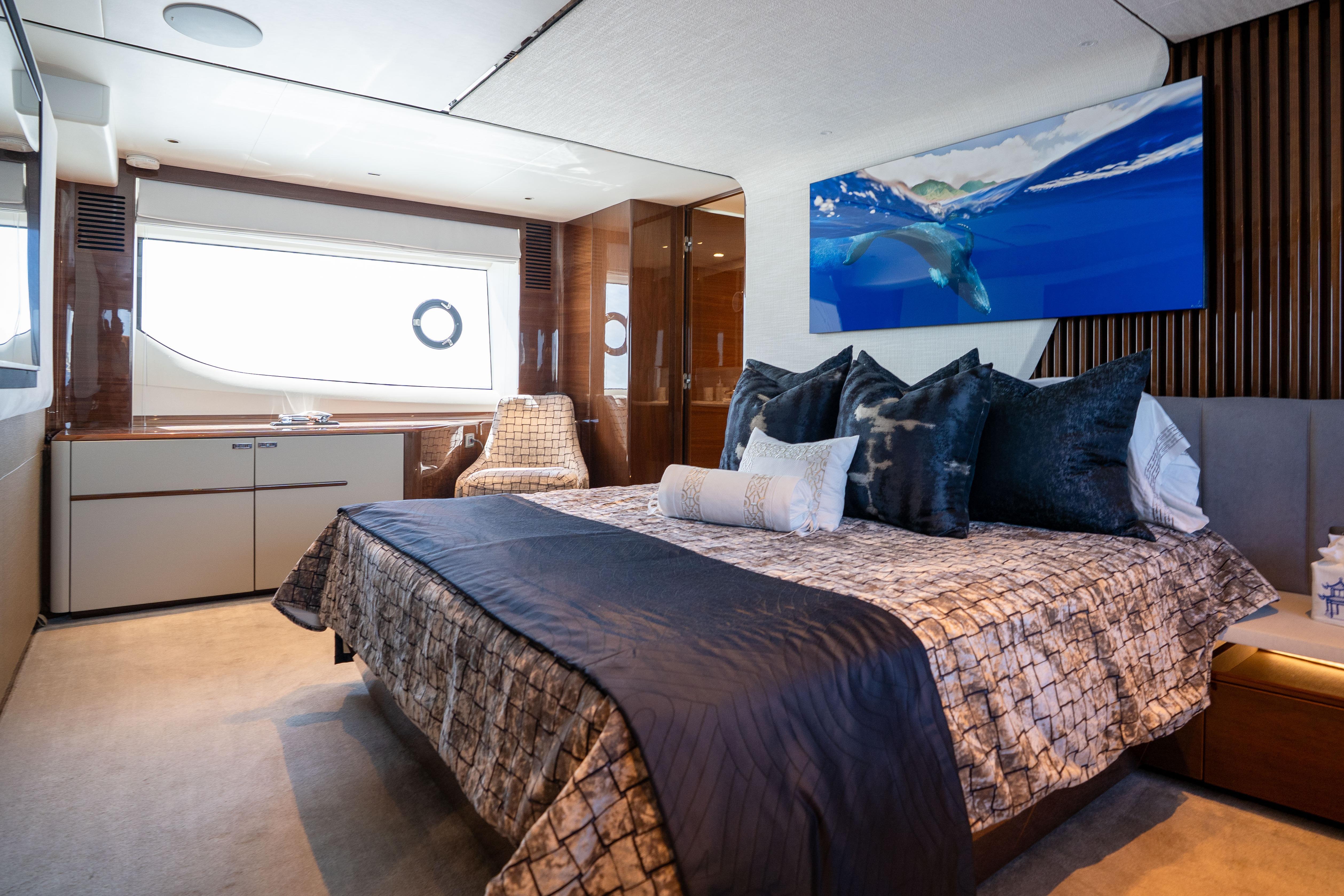 Luxurious bedroom interior on a 2020 Princess Y85 yacht, featuring elegant decor and ocean artwork.