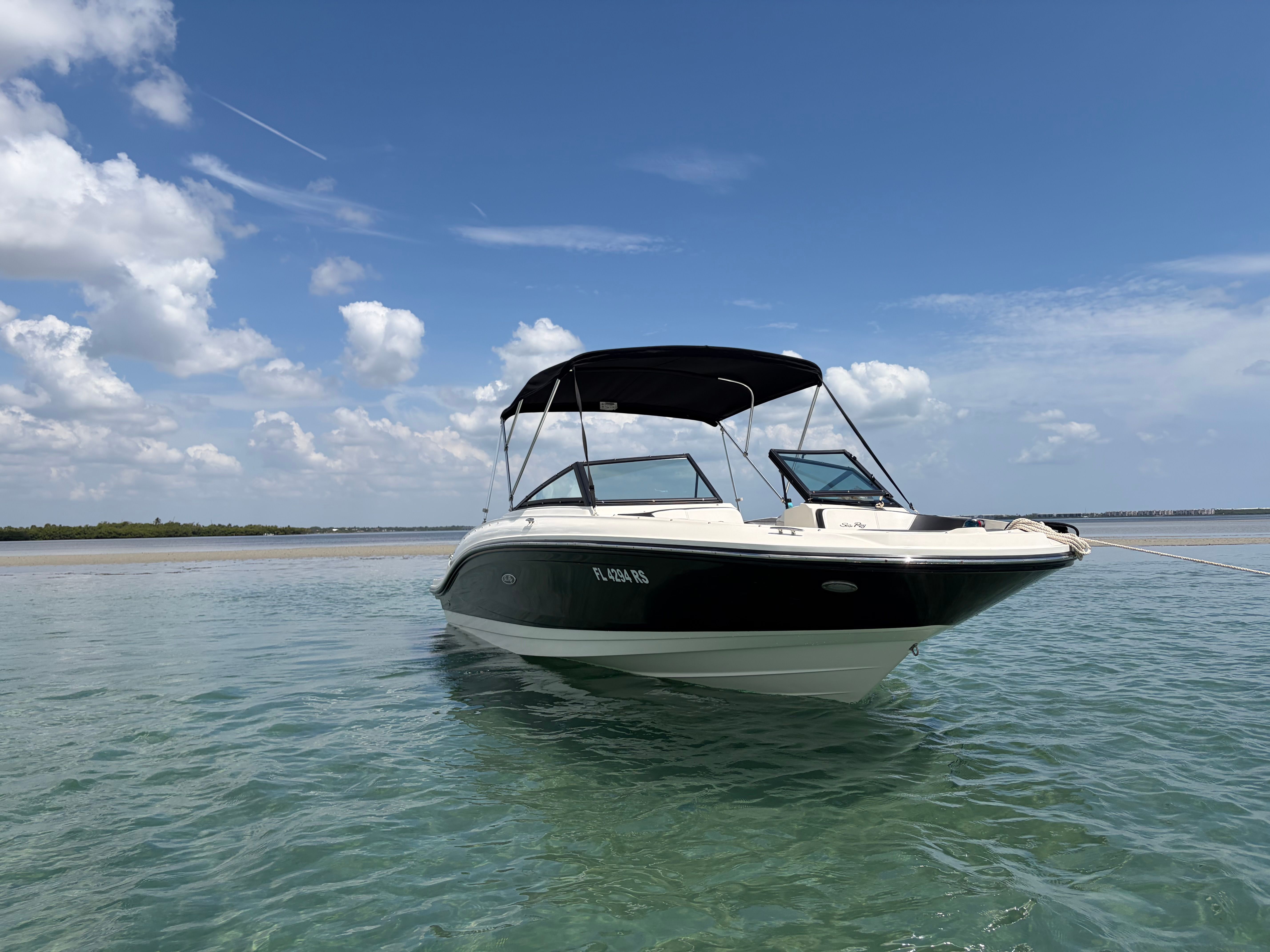 A 2018 Sea Ray SPX 210 boat floating in clear water under a blue sky.