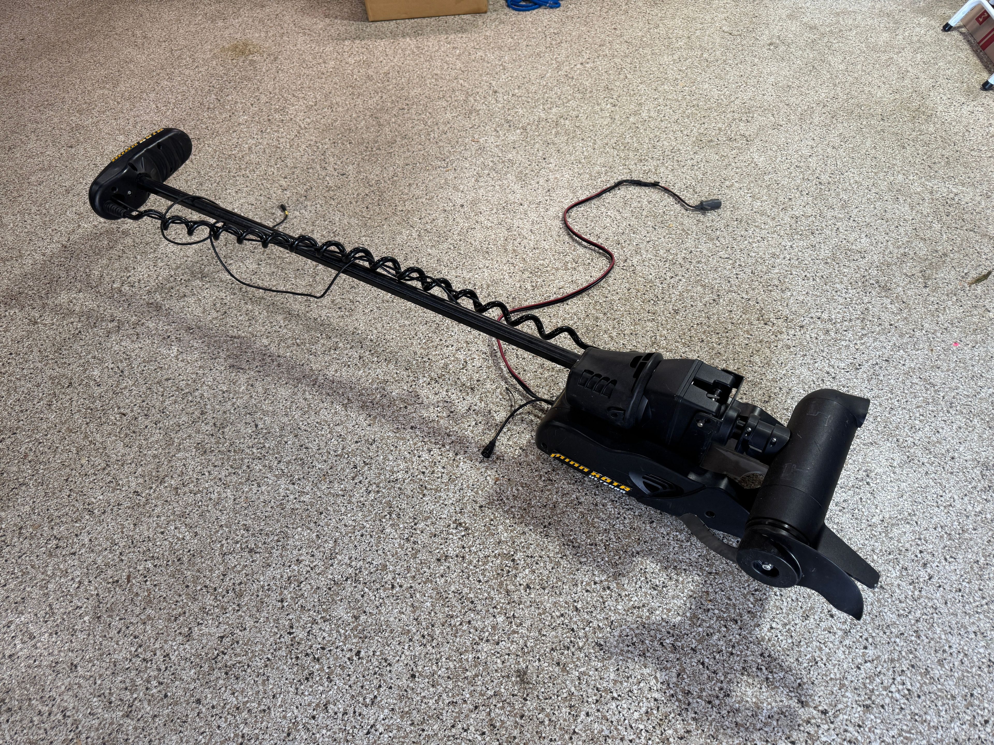 A boat motor lies on a gray floor.