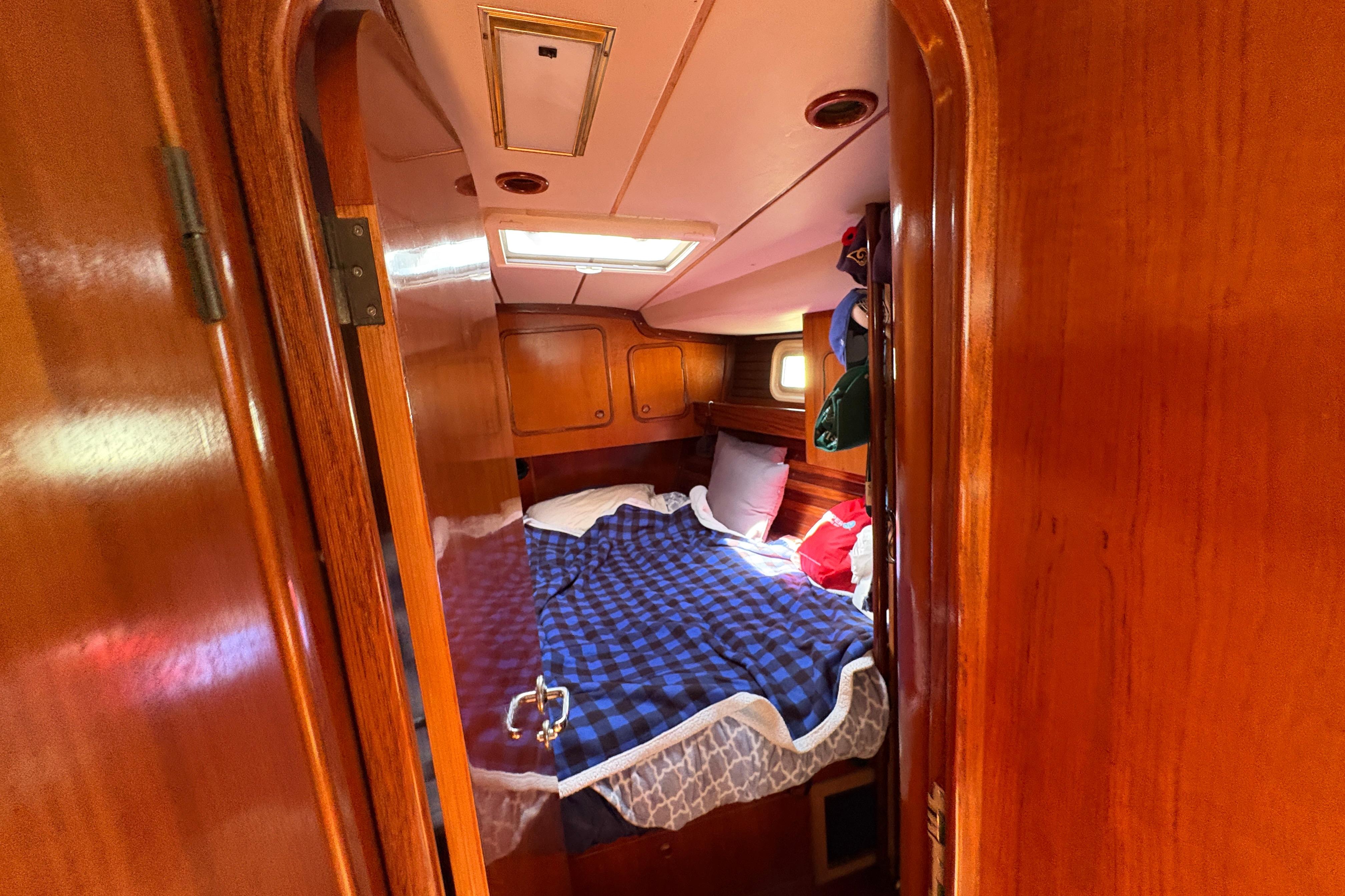 Cozy cabin interior of 1990 Beneteau Oceanis 500 sailboat with wooden finish and bed.