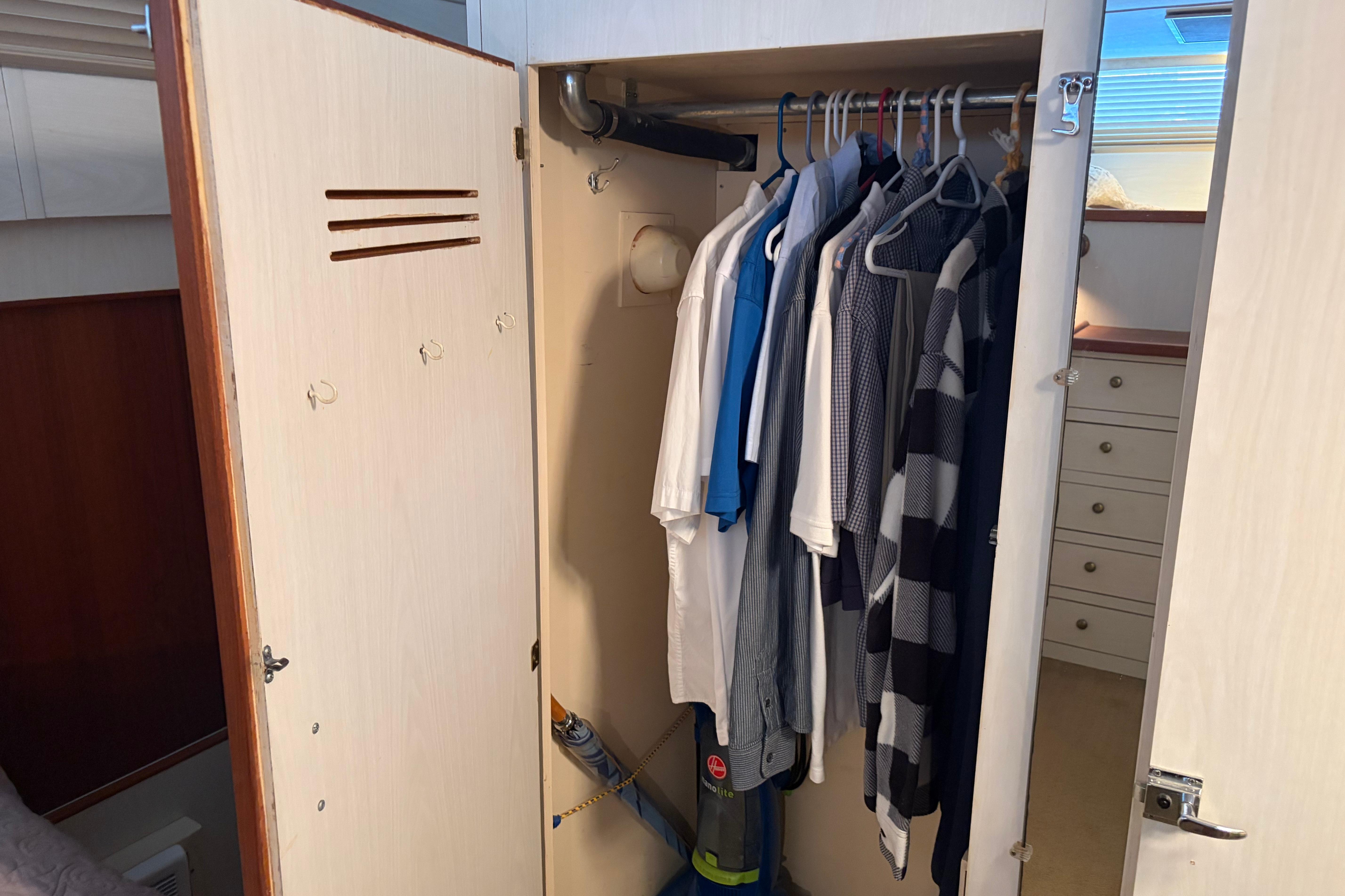 Wardrobe inside 1971 Chris-Craft 42 Commander yacht, featuring hanging clothes and a vacuum cleaner.