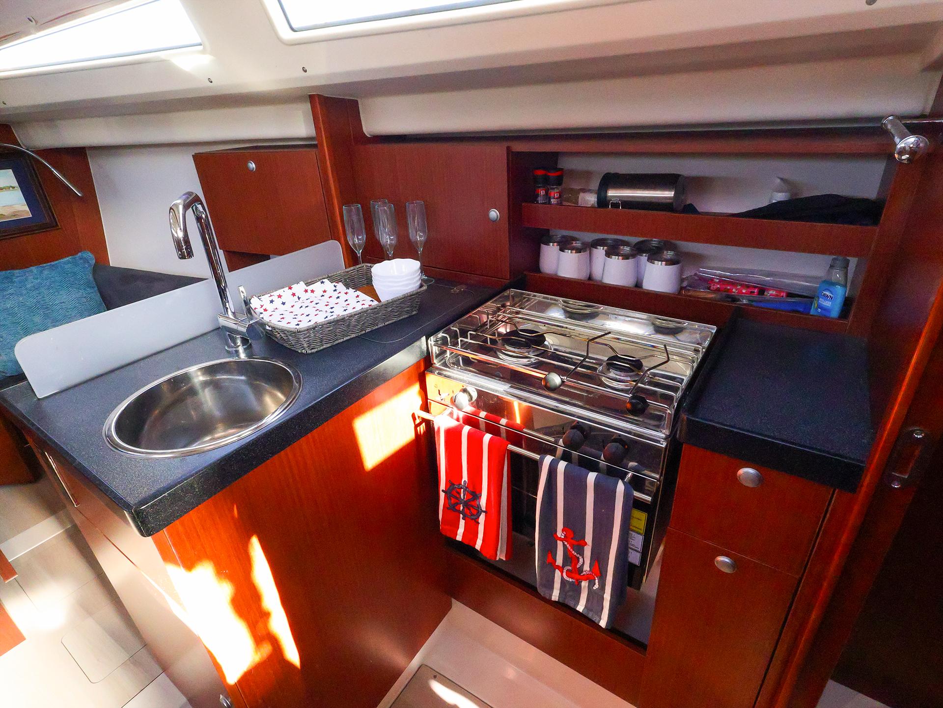 2018 Hanse 315 yacht kitchen with sink, stove, and wooden cabinetry.