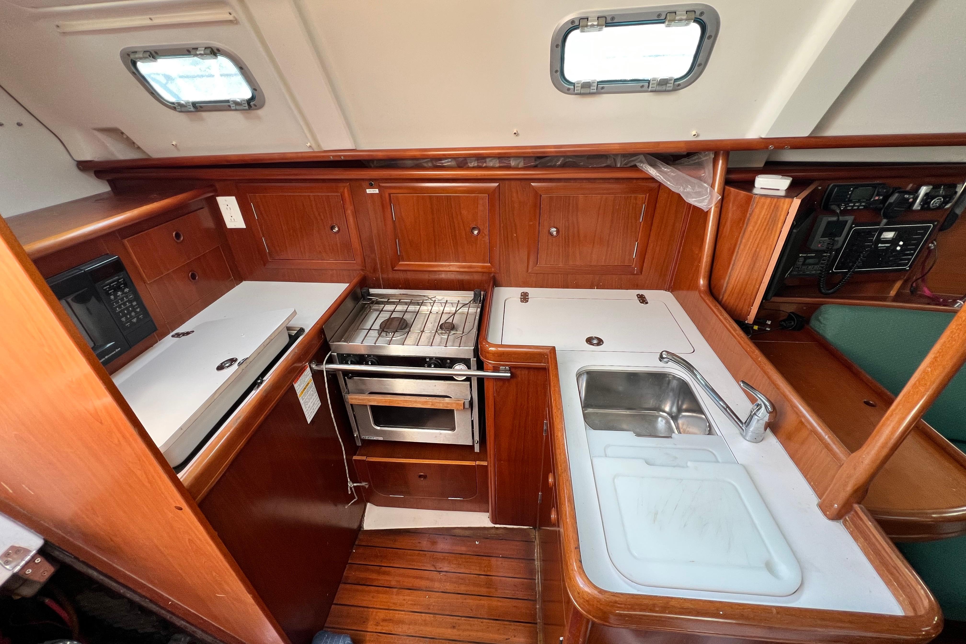 2001 Beneteau 331 yacht kitchen with stove, sink, and wooden cabinetry.
