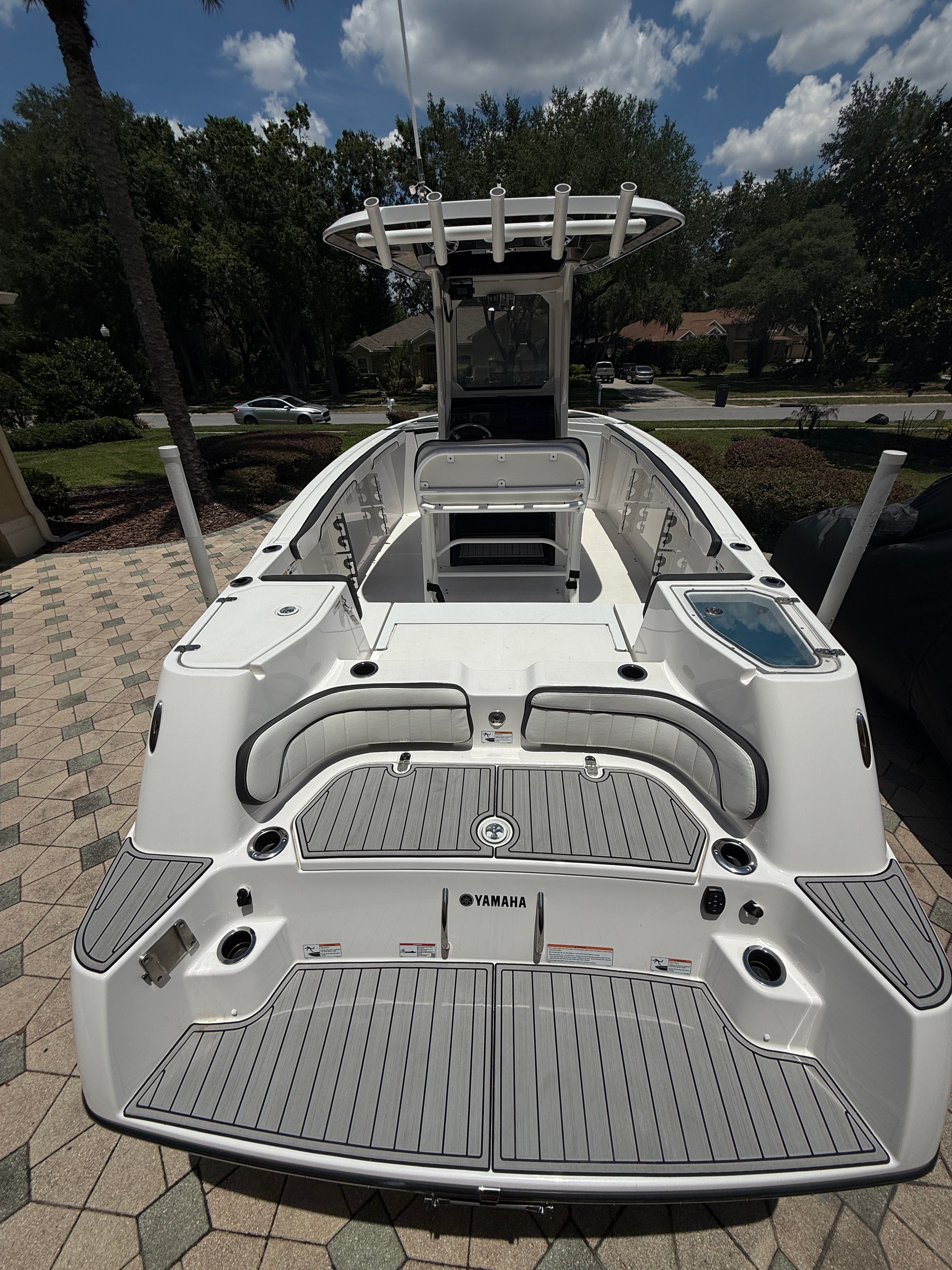 Yamaha 252 FSH Sport 2024 on a paved area, featuring a T-top and spacious deck.