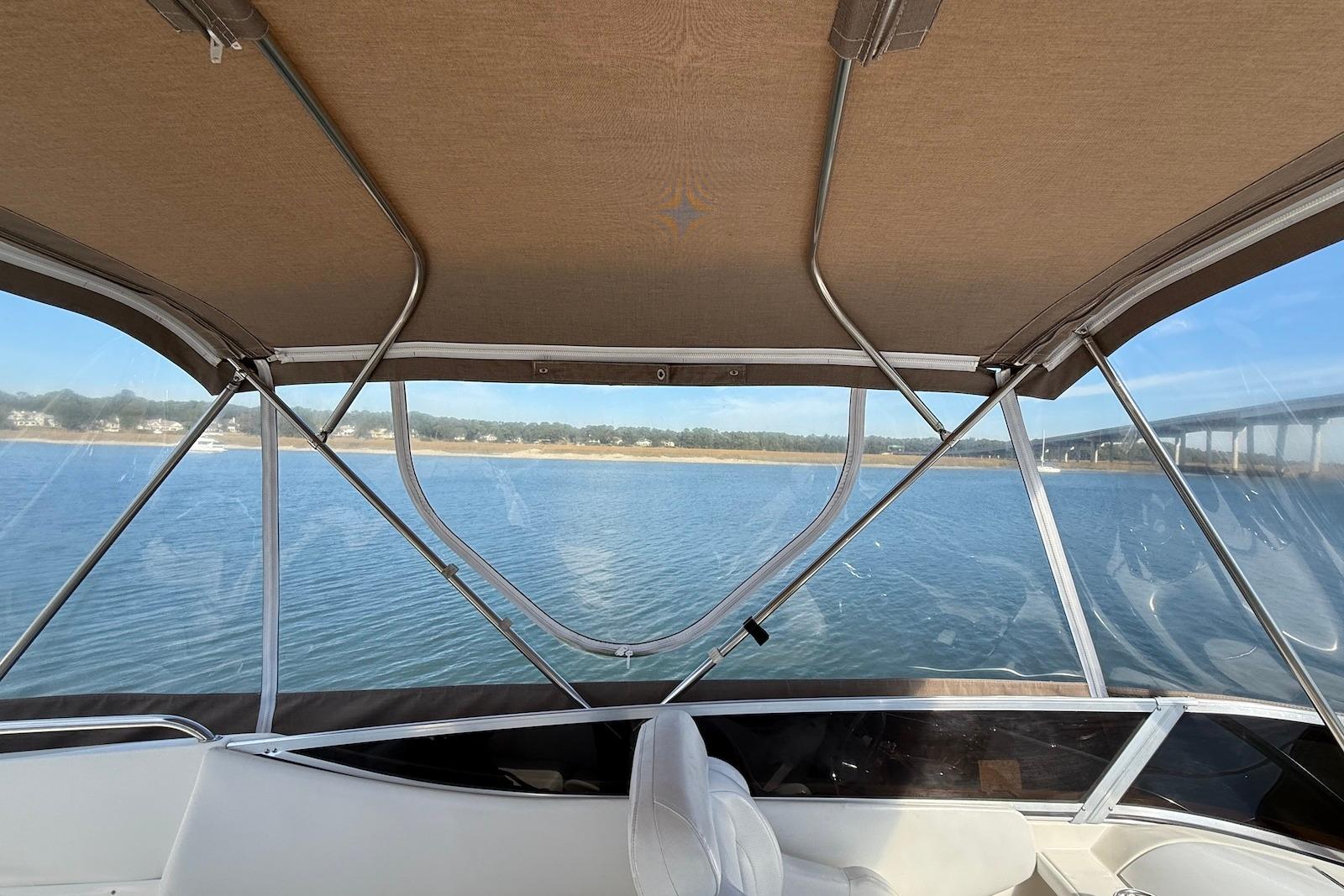 2003 Regal Commodore 3880 boat interior with canopy, overlooking serene water and distant shoreline.