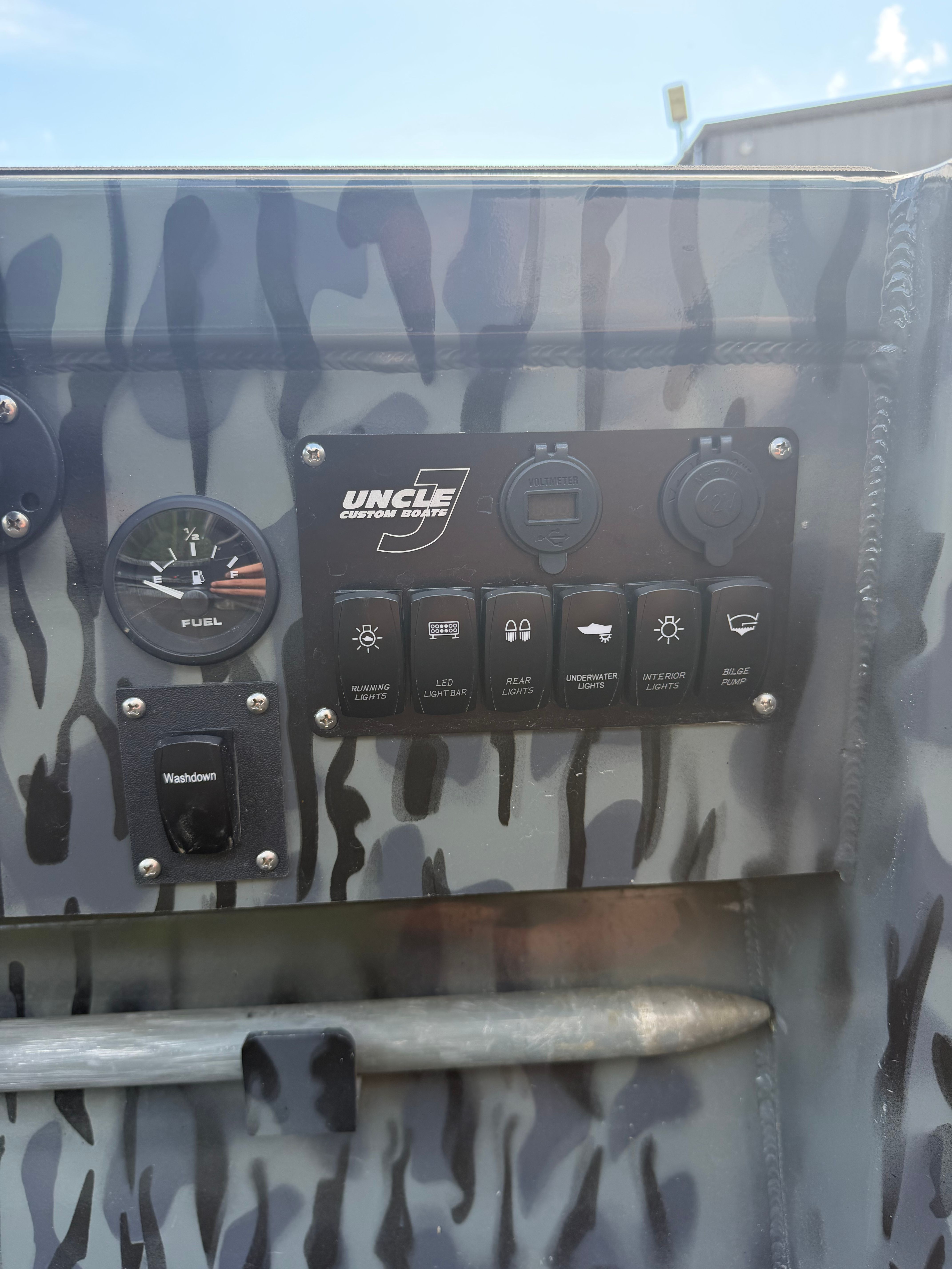Close-up of a boat dashboard with various switches and a fuel gauge.