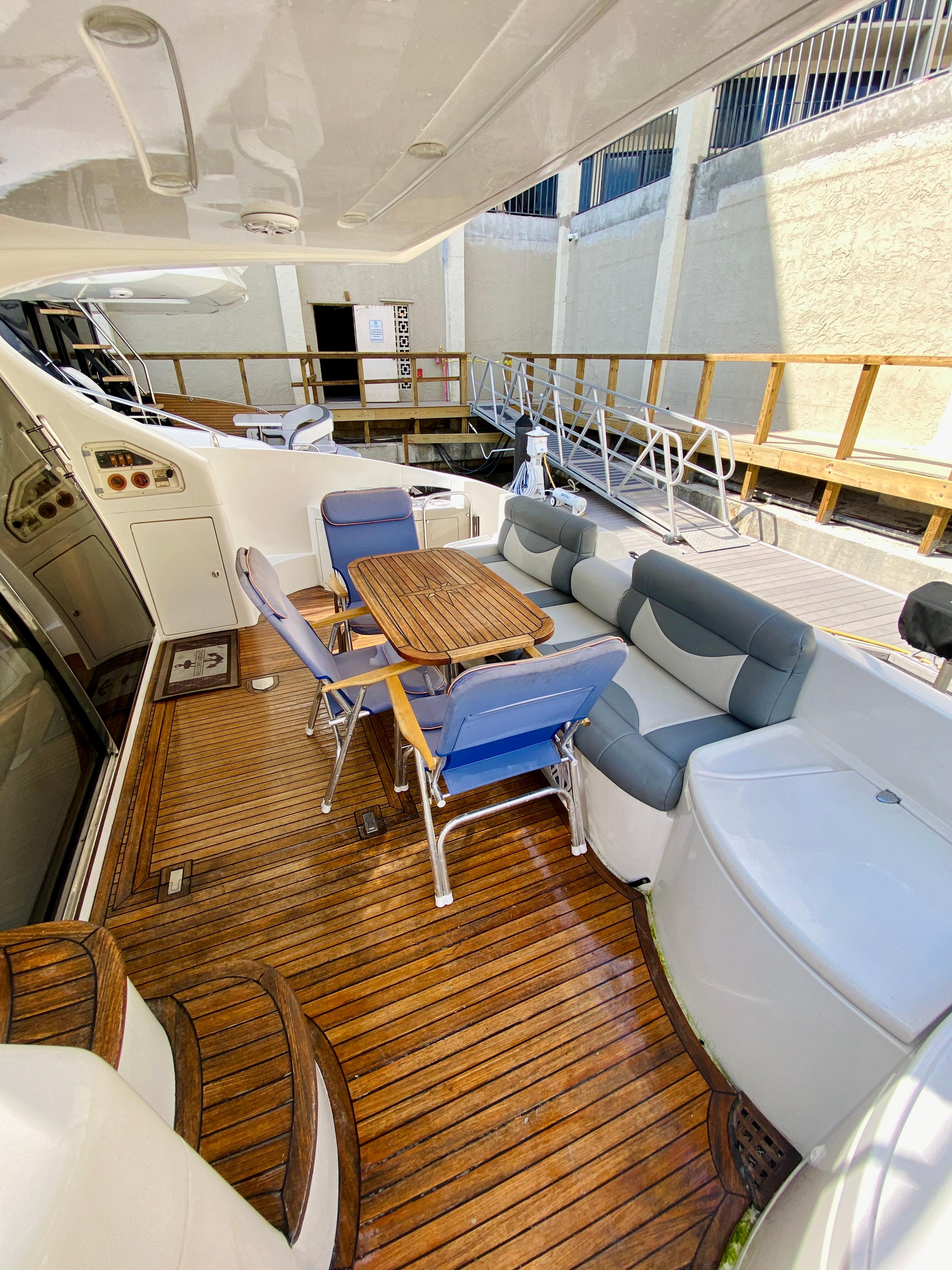 Luxurious 2002 Azimut 55 yacht deck with seating and wooden flooring.