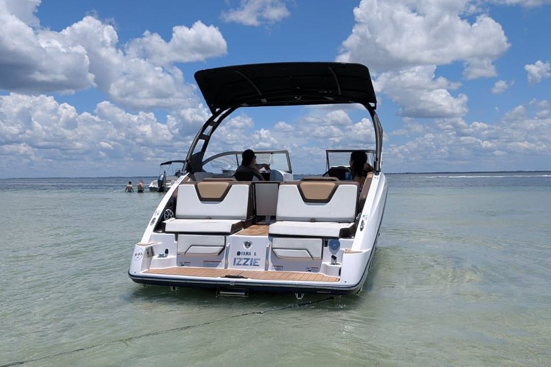 A 2021 Yamaha 252SD boat in shallow water, featuring an open deck and sunshade.