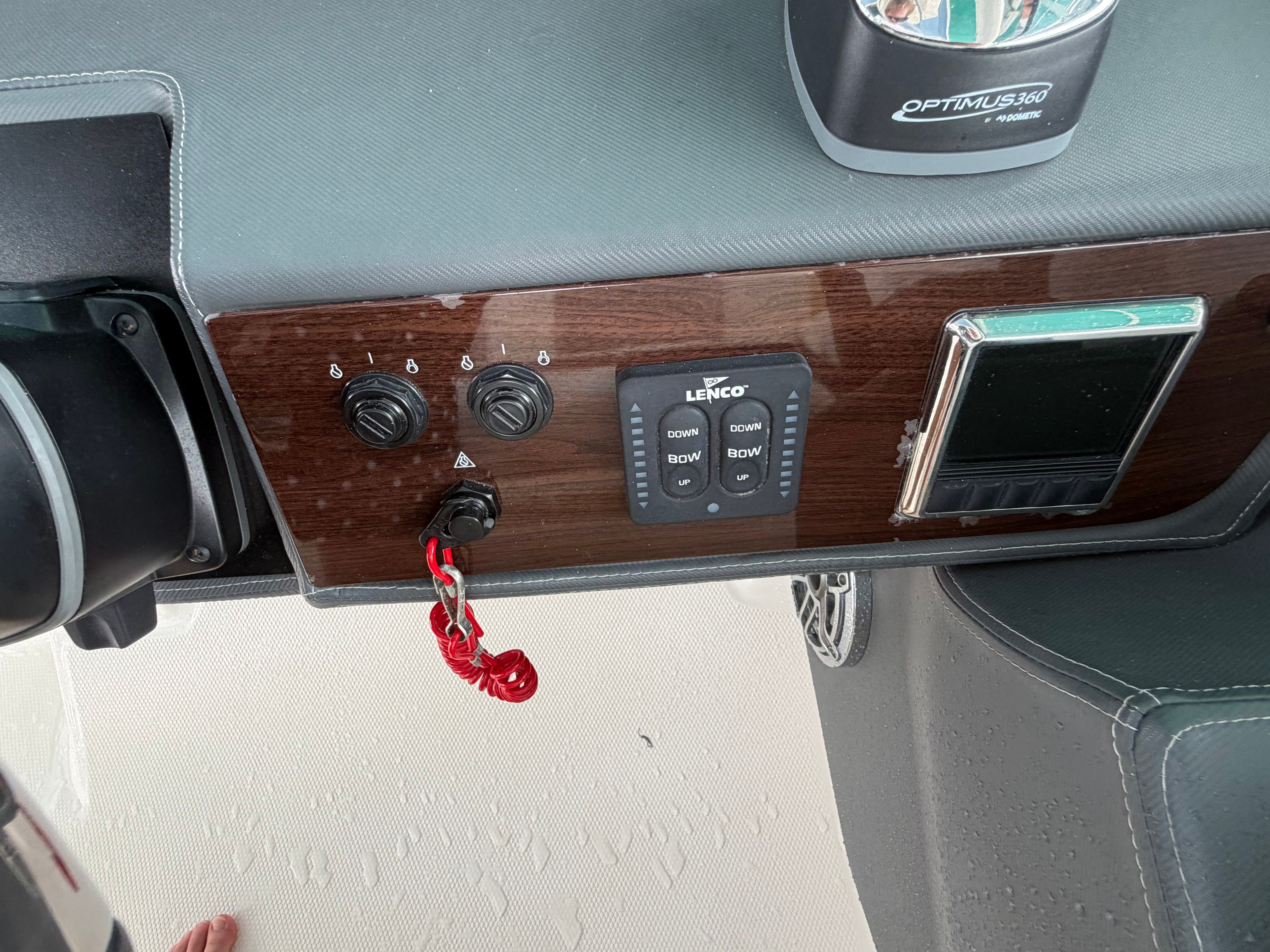 Close-up of a boat's helm with switches and a steering wheel.