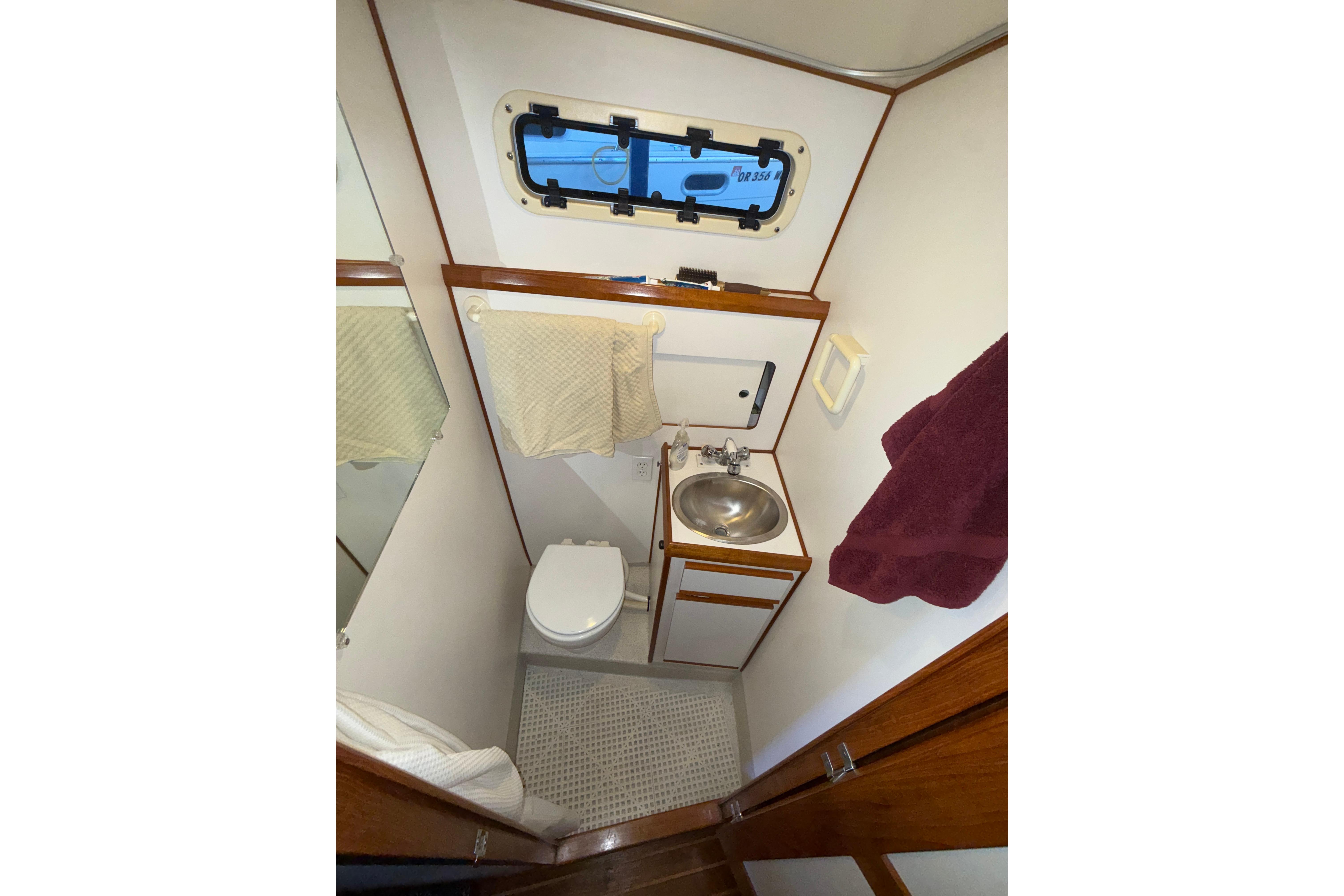 Compact bathroom in a 1997 Norstar 301 boat with sink, toilet, and porthole.