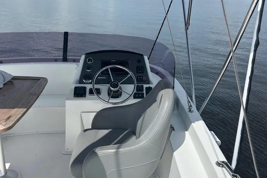 2017 Beneteau Swift Trawler 34 helm with steering wheel and controls on calm water.