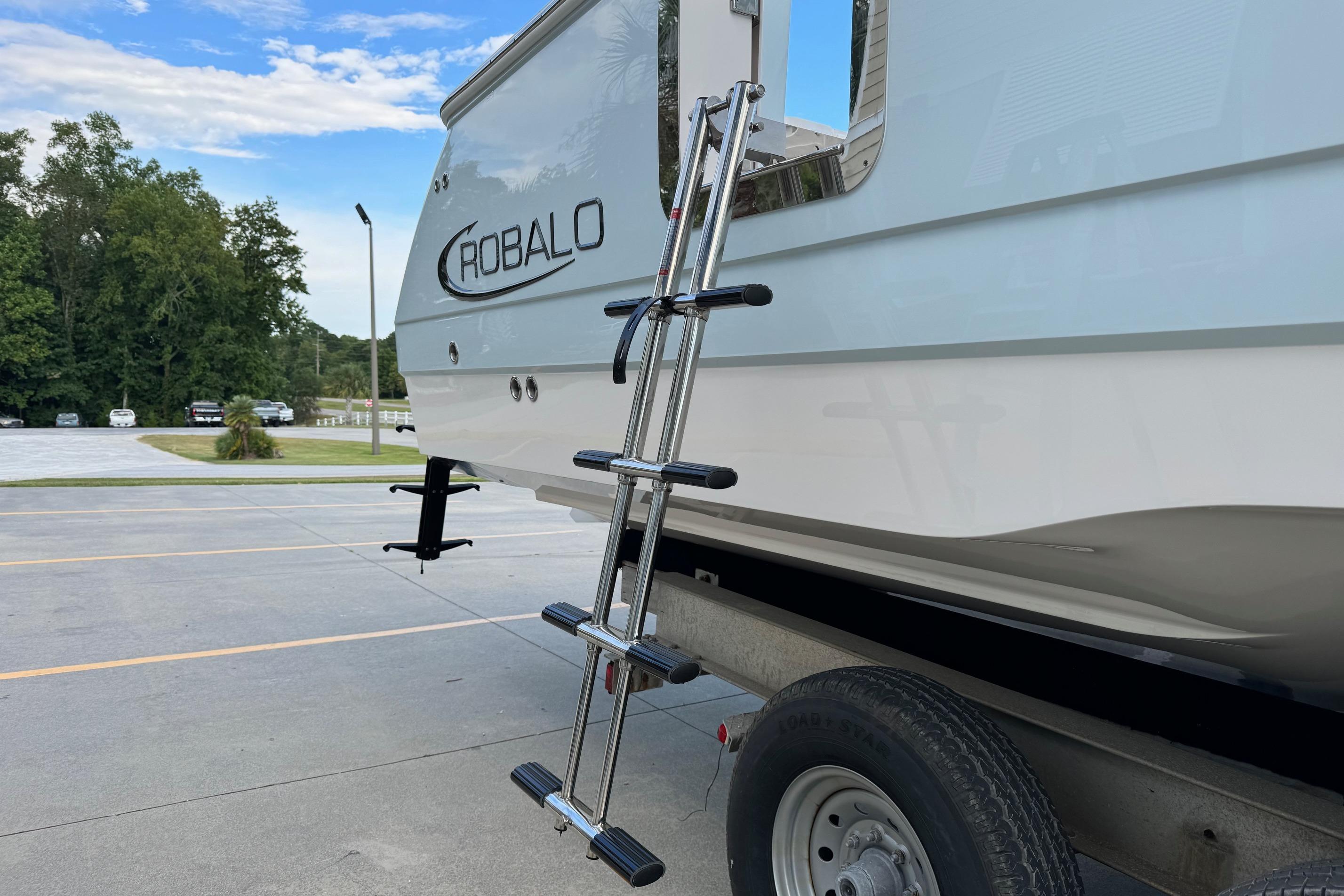 2025 Robalo R360 Center Console boat on trailer with ladder, parked outdoors.