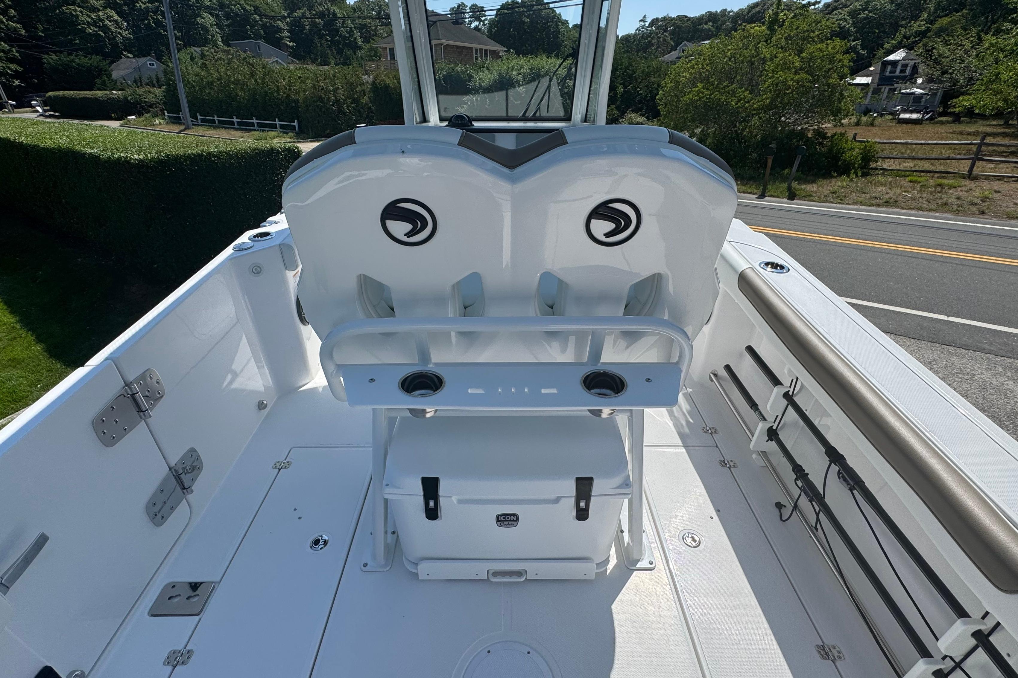 2026 Edgewater 250CC boat interior with dual seats and rod holders, parked near a road.
