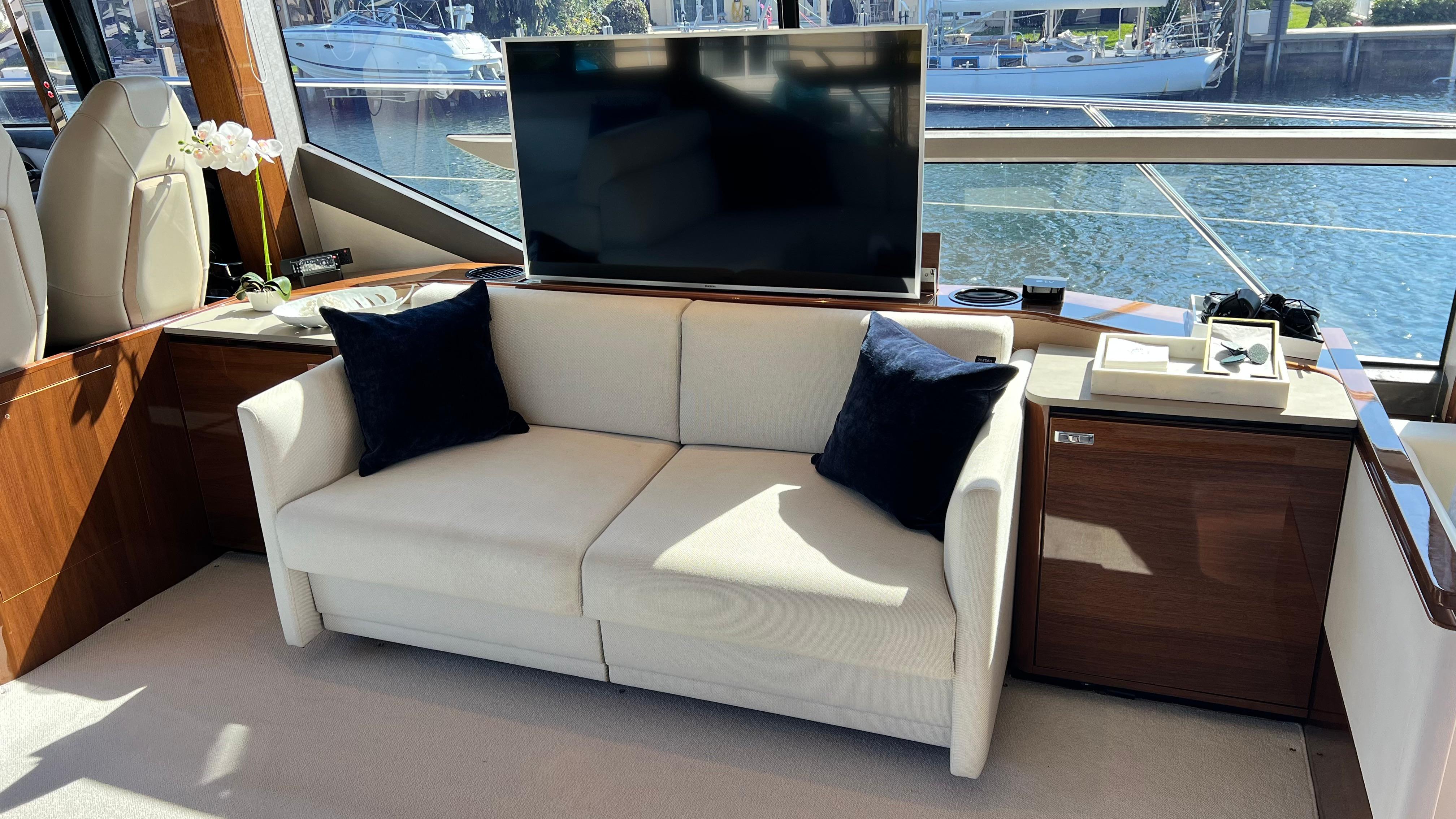 Luxurious 2019 Princess F62 yacht interior with sofa, TV, and waterfront view.